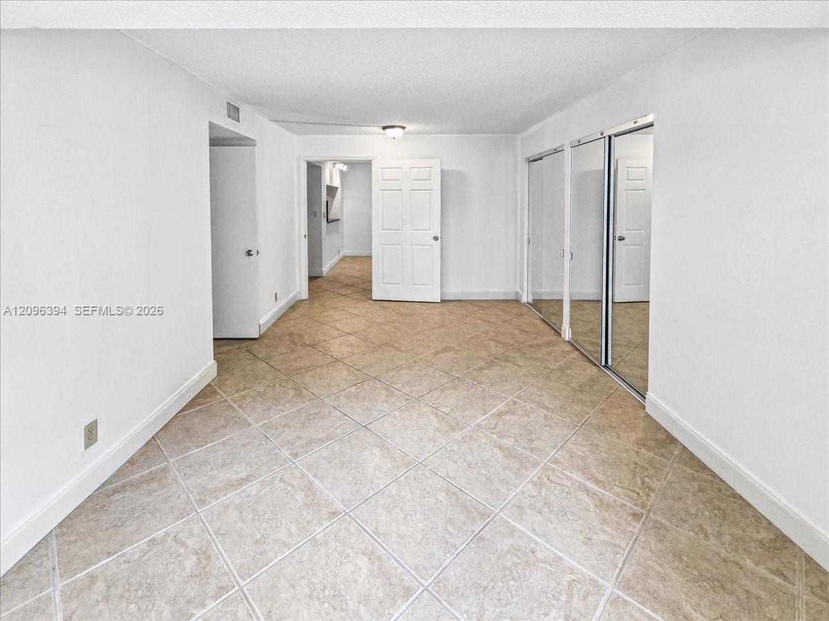 Interior space featuring large-format tile flooring, dual mirrored sliding-door closets, and six-panel interior doors
