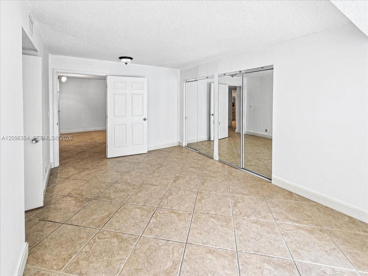 Ceramic tile flooring laid in a diagonal pattern, full-height mirrored sliding closet doors, and solid-core interior passage doors