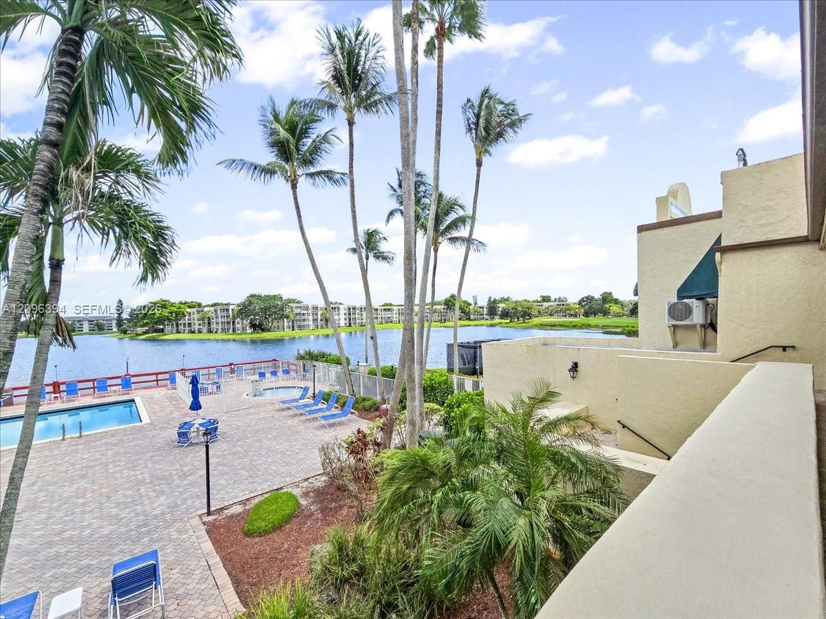 Patio featuring stone-paver decking, swimming pool, in-ground spa, mature palm trees, and water frontage