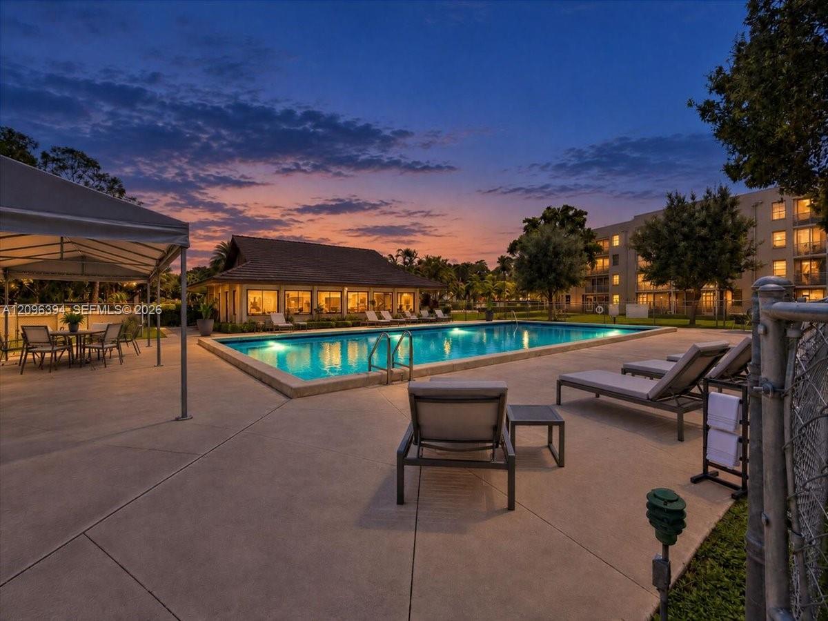 Outdoor swimming pool featuring a concrete deck, covered pavilion, and metal perimeter fencing