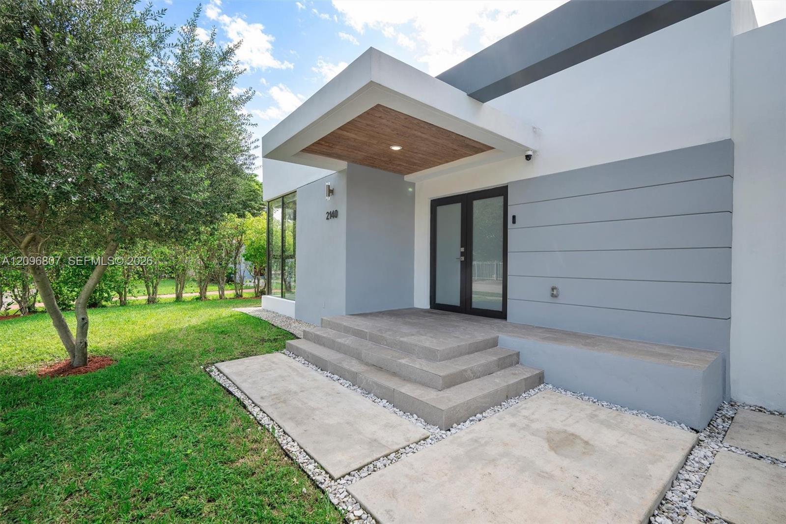 Modern facade featuring a cantilevered entryway with a wood-finish ceiling, concrete front steps, dual-glass entry doors, and horizontal panel siding