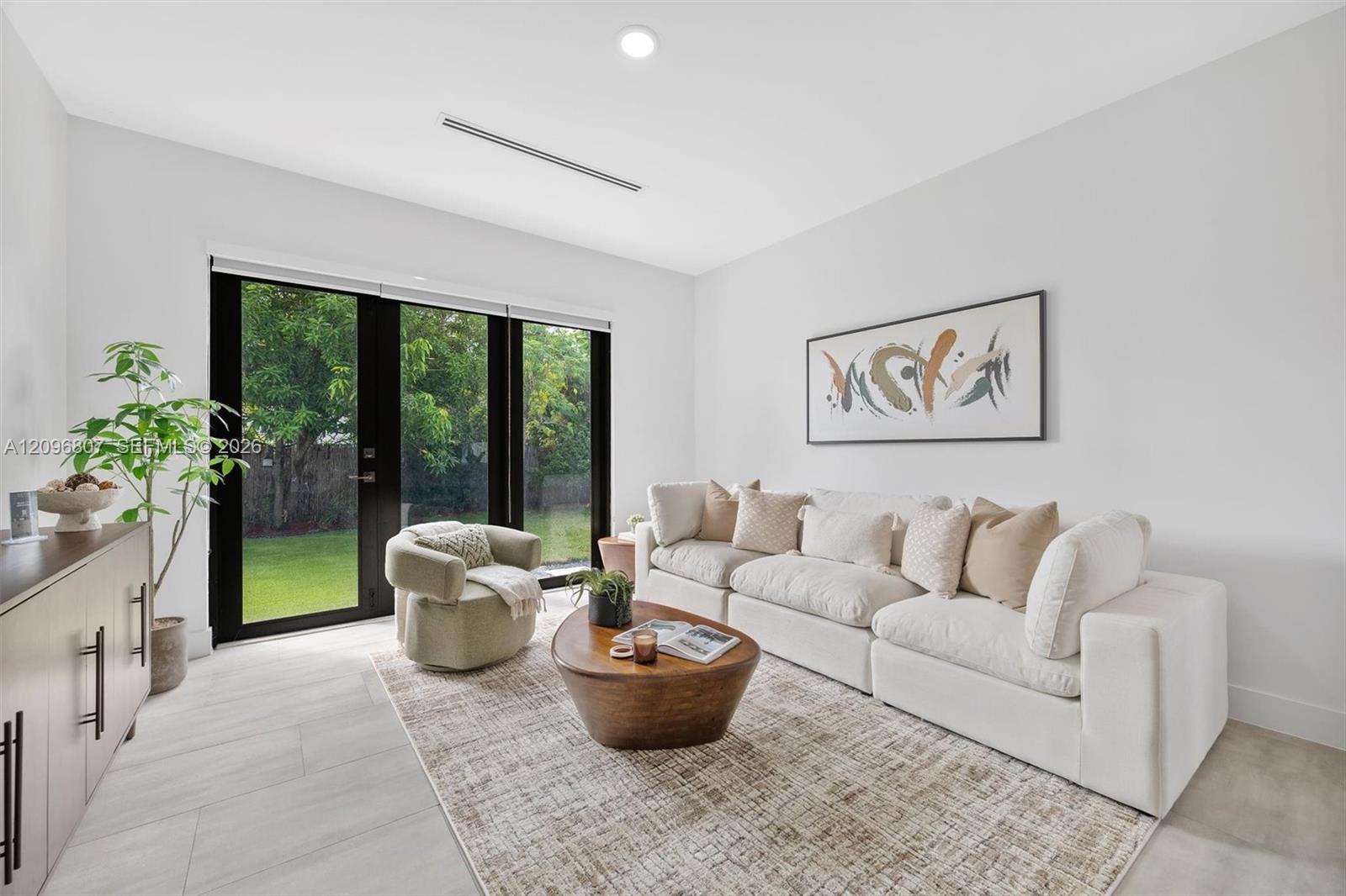 Neutral-toned large-format tile flooring, recessed ceiling lighting, and black-framed glass paneled doors featuring lever hardware