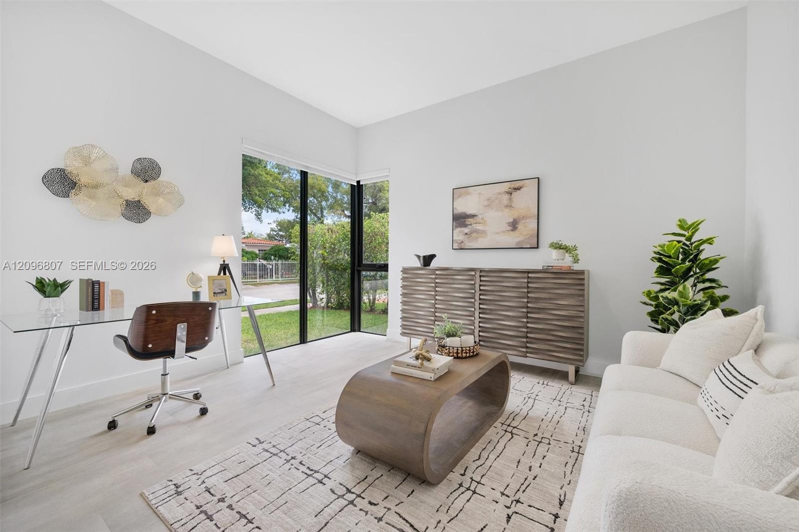 Neutral interior space featuring high ceilings, wood-finish flooring, and floor-to-ceiling corner windows with black frames