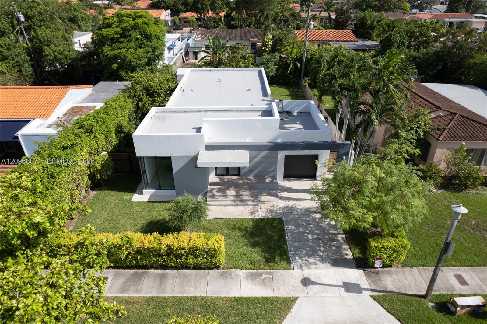 Modern exterior featuring a flat roofline, smooth stucco finish, single-car garage, and a paved driveway Modern exterior featuring a flat roofline, smooth stucco finish, single-car garage, and a paved driveway