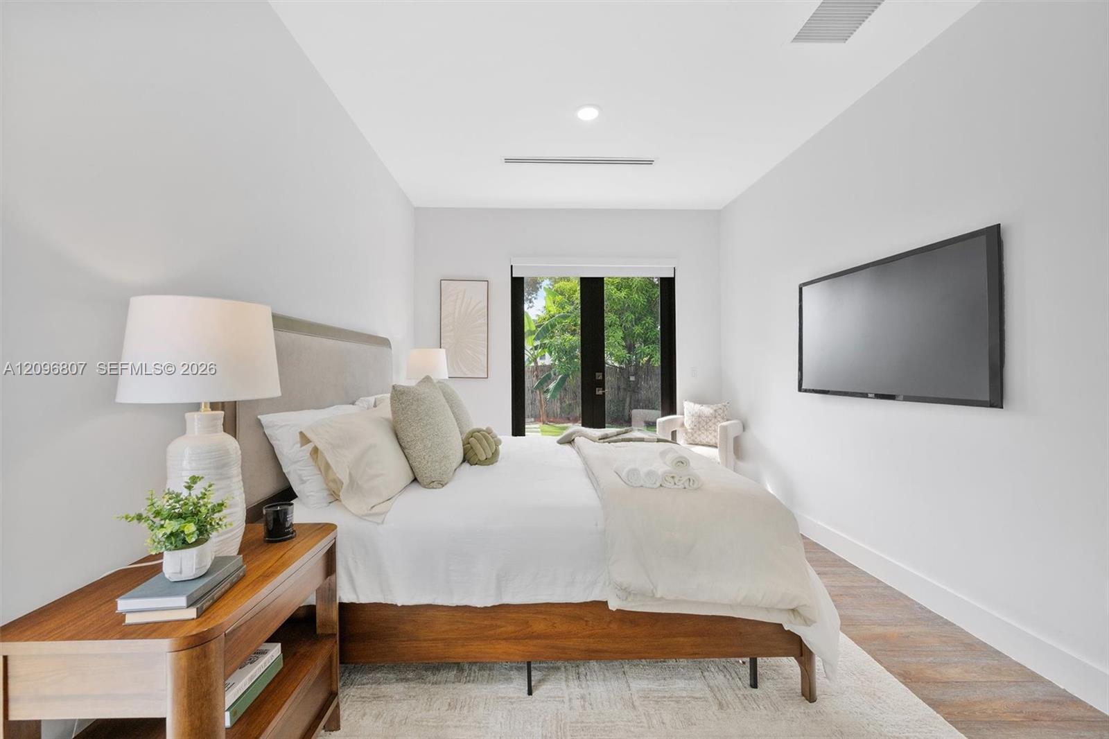 Wood-finish flooring, recessed lighting, and full-height glass-paned doors leading to exterior grounds