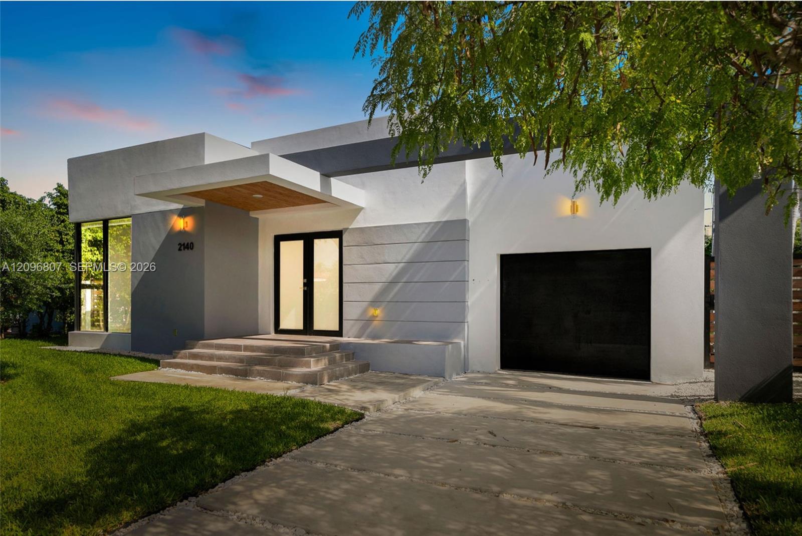 Modern exterior featuring a smooth stucco facade, dual-tone architectural detailing, a covered entrance with wood-paneled ceiling, and a concrete driveway Modern exterior featuring a smooth stucco facade, dual-tone architectural detailing, a covered entrance with wood-paneled ceiling, and a concrete driveway
