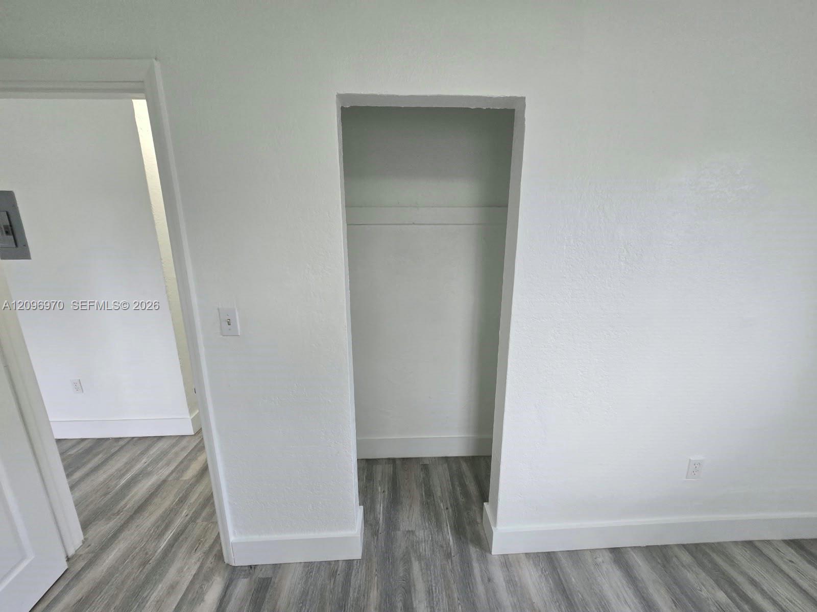 Built-in closet featuring a shelf and rod, complemented by wood-finish flooring and neutral wall tones
