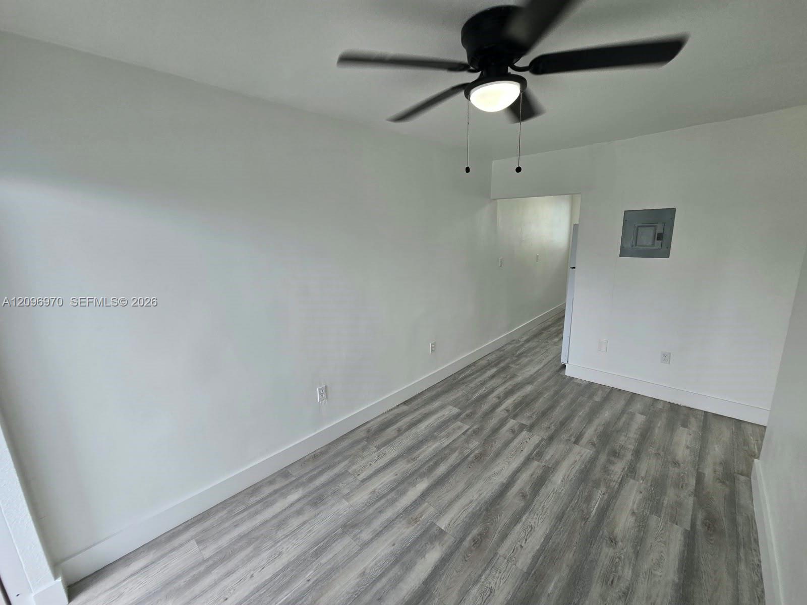 Interior space featuring wood-finish flooring, neutral wall tones, and a ceiling-mounted light fixture with a fan Interior space featuring wood-finish flooring, neutral wall tones, and a ceiling-mounted light fixture with a fan