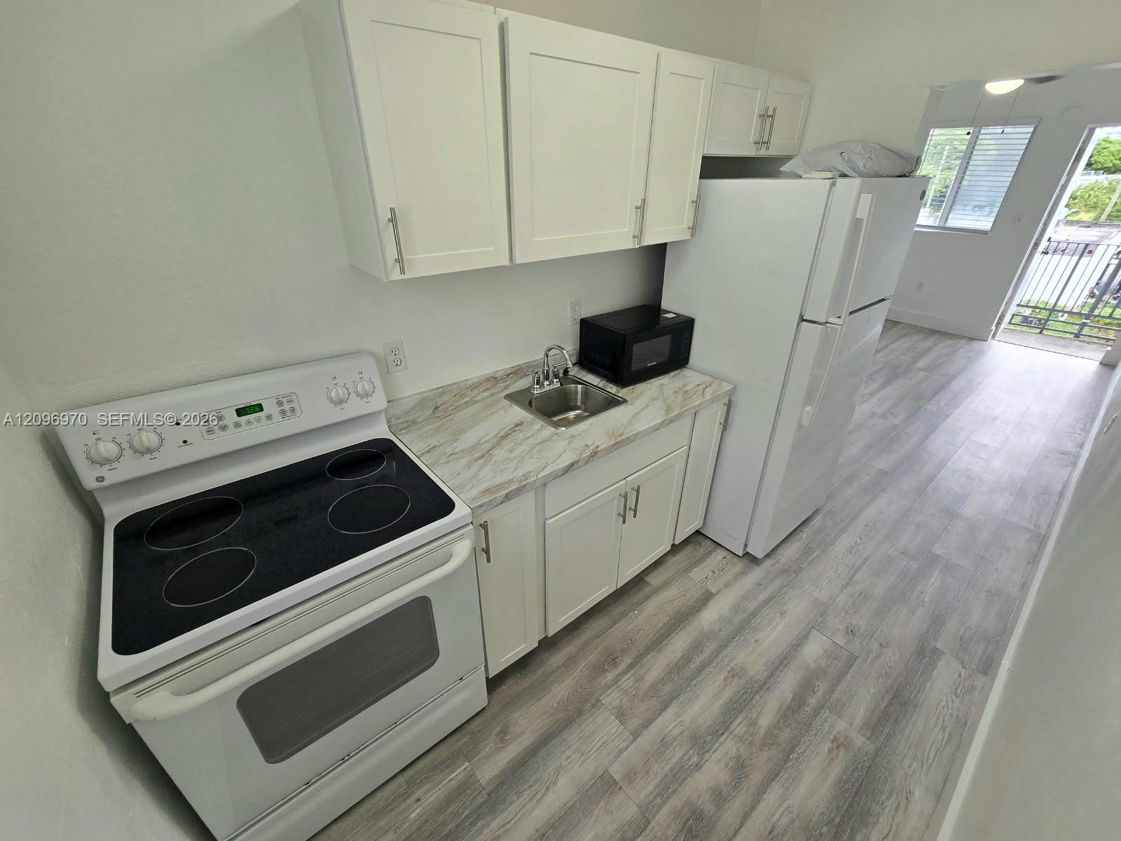 Kitchen featuring white shaker-style cabinetry, stone-pattern laminate countertops, wood-finish flooring, and a full-size white electric range Kitchen featuring white shaker-style cabinetry, stone-pattern laminate countertops, wood-finish flooring, and a full-size white electric range