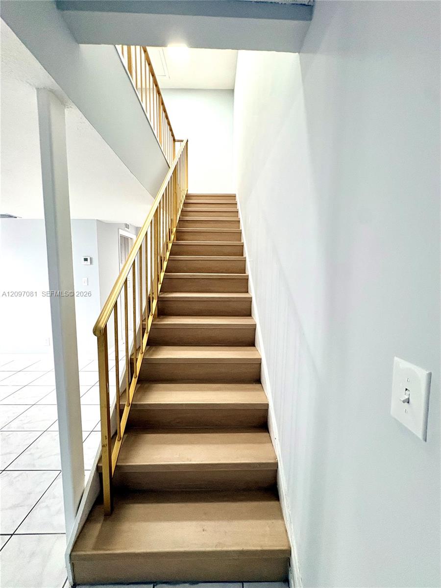 Staircase featuring wood-finish treads and a metal vertical-bar railing
