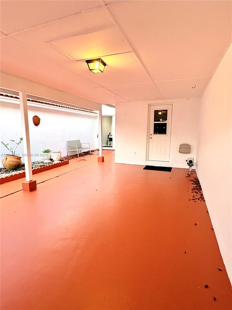 Covered patio featuring a solid-surface floor, recessed lighting, and a garden bed bordered by decorative stone