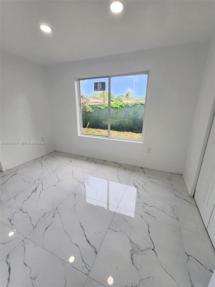 Large-format stone-finish floor tiles featuring veined detailing, recessed ceiling lighting, and a large horizontal sliding window
