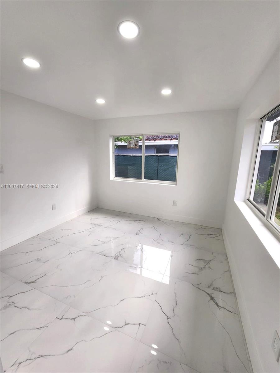 Polished stone-finish tile flooring, recessed ceiling lighting, and large-format sliding windows