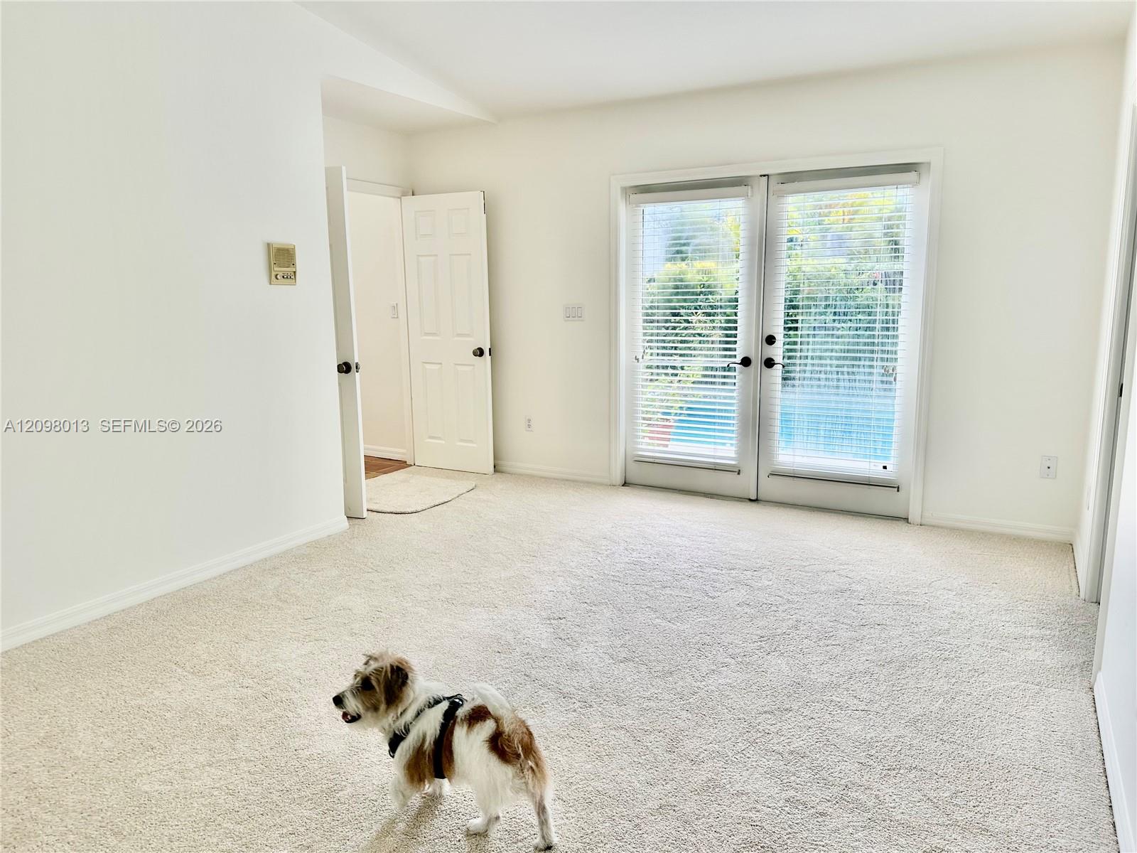 Primary bedroom with high ceiling ceiling, and dual-pane glass French doors to pool.
