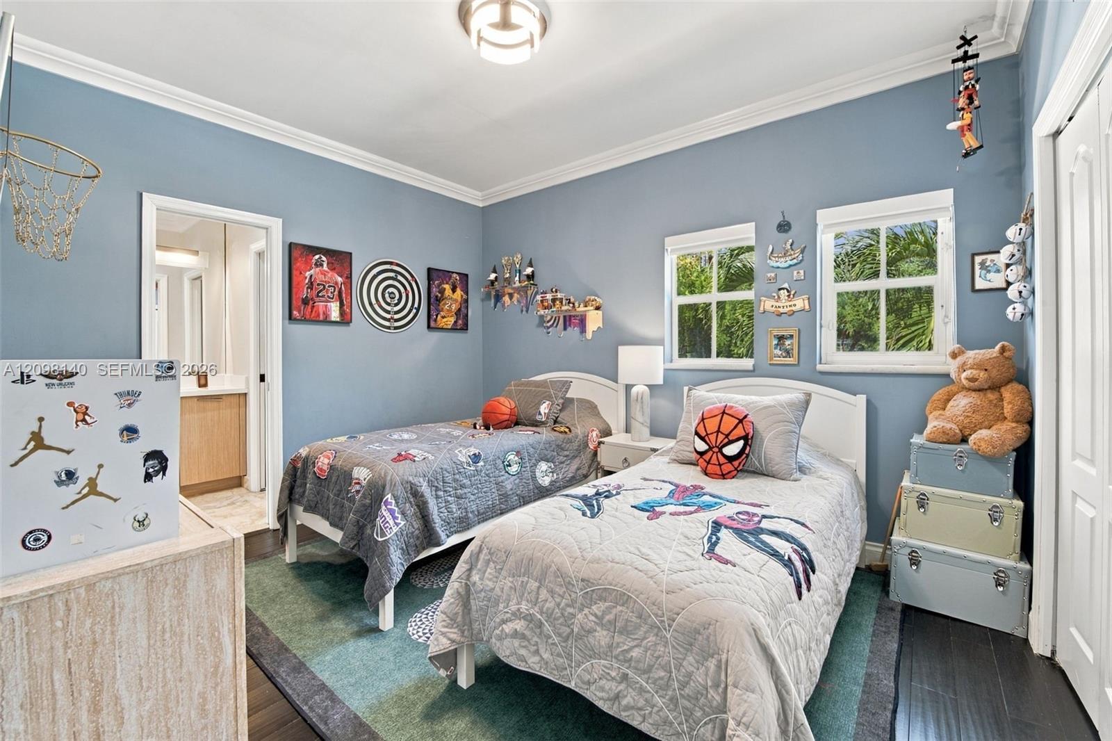 Bedroom featuring dark wood-finish flooring, crown molding, double-hung windows with exterior mullions, and an attached en-suite bathroom with a built-in vanity