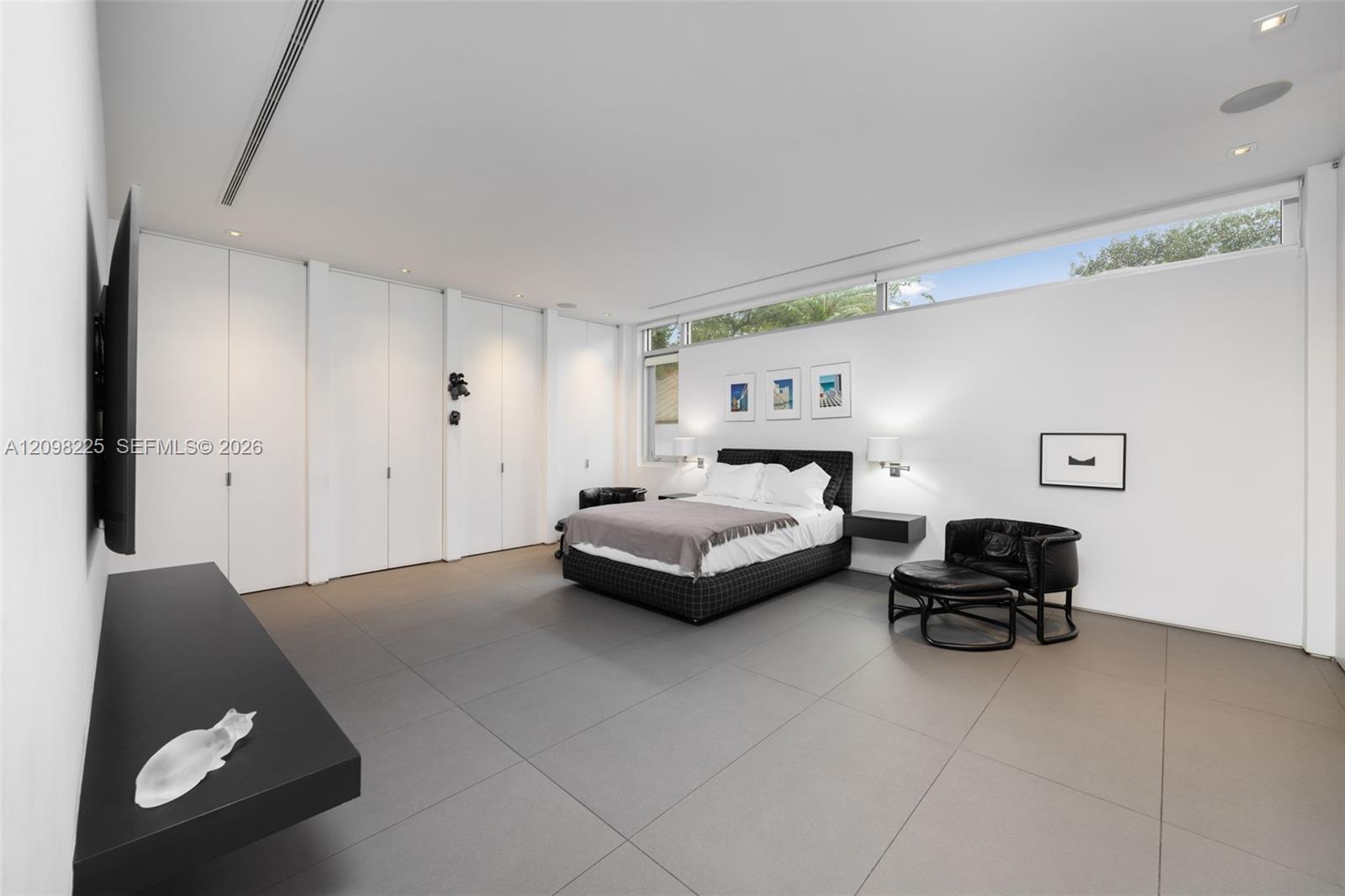 Expansive room featuring large-format tile flooring, built-in floor-to-ceiling storage cabinetry, recessed lighting, and horizontal clerestory windows