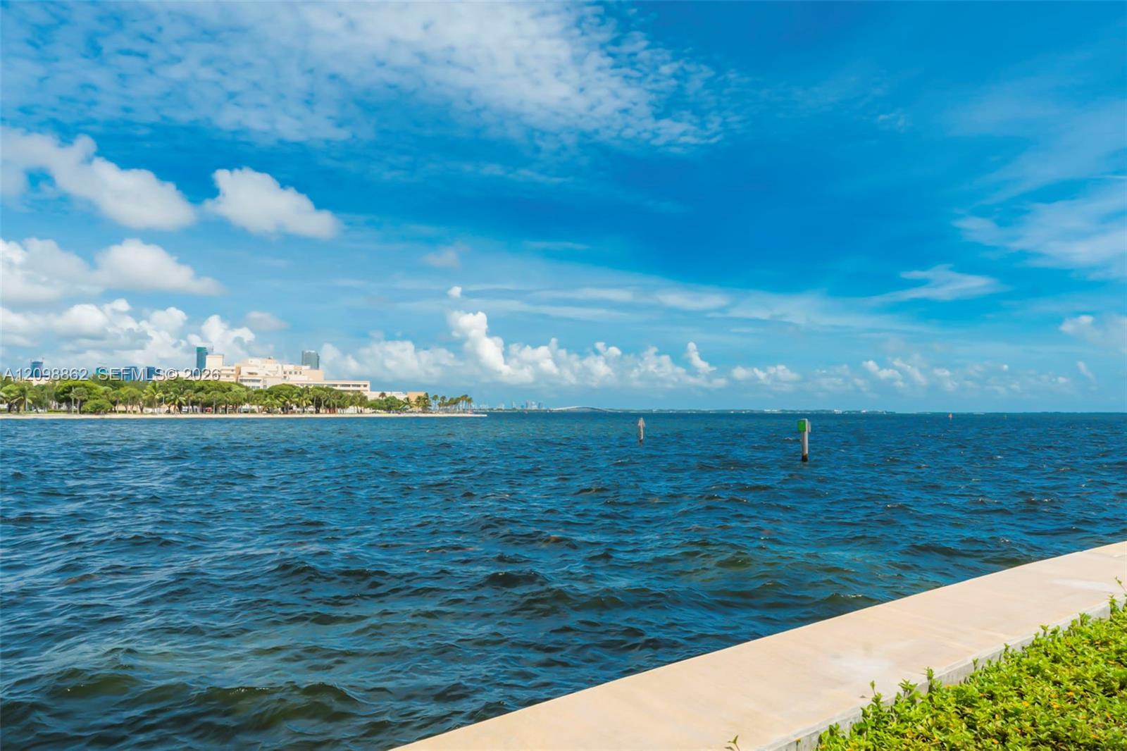 Waterfront property featuring a concrete seawall and manicured shrubbery