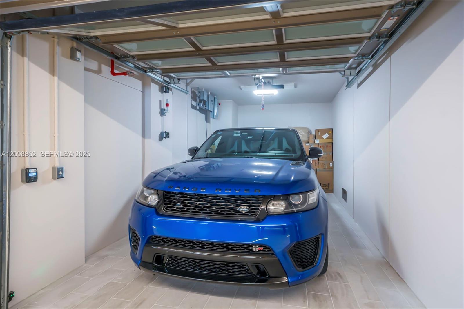 Enclosed garage featuring tile flooring, a multi-panel glass-inset sectional door, and an overhead lighting fixture