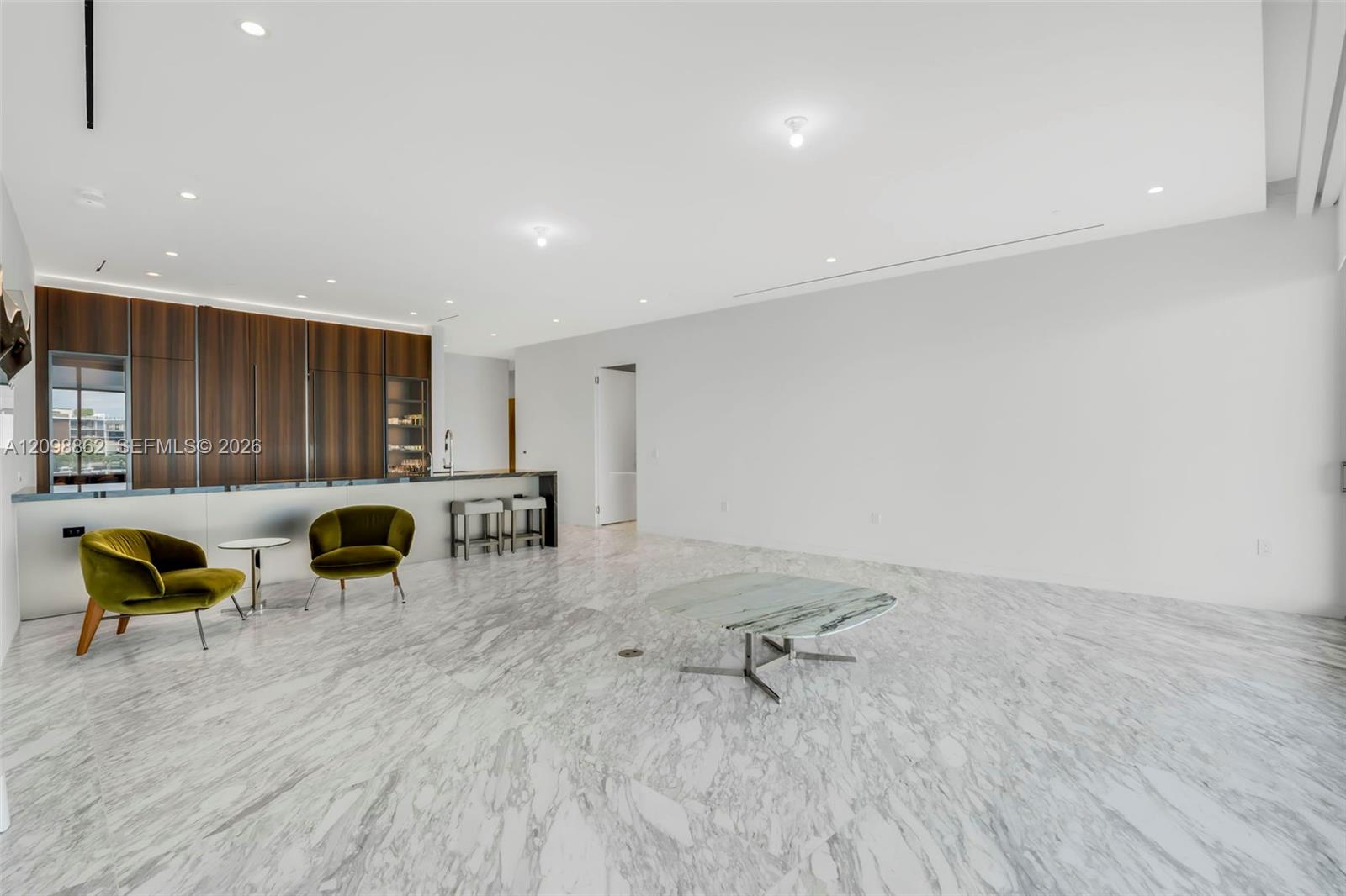 Polished stone flooring, custom wood-veneer cabinetry, recessed ceiling lighting, and a built-in bar counter