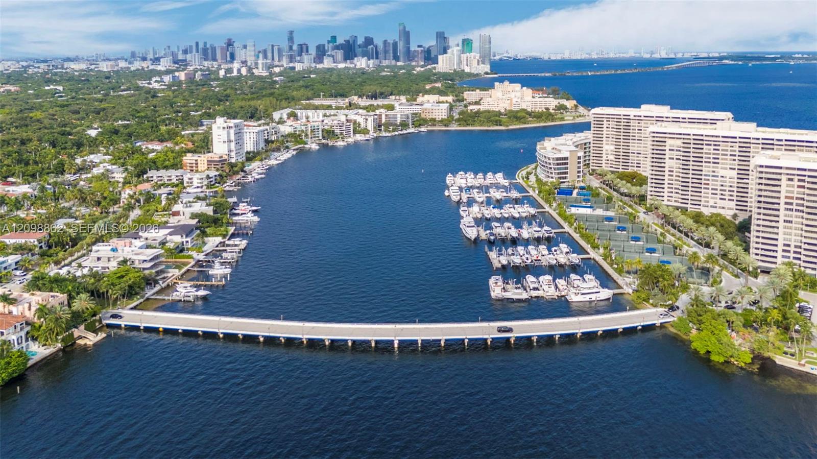 Aerial perspective featuring a waterfront marina, deep-water access, concrete bridge infrastructure, and high-rise residential architecture with city skyline backdrop