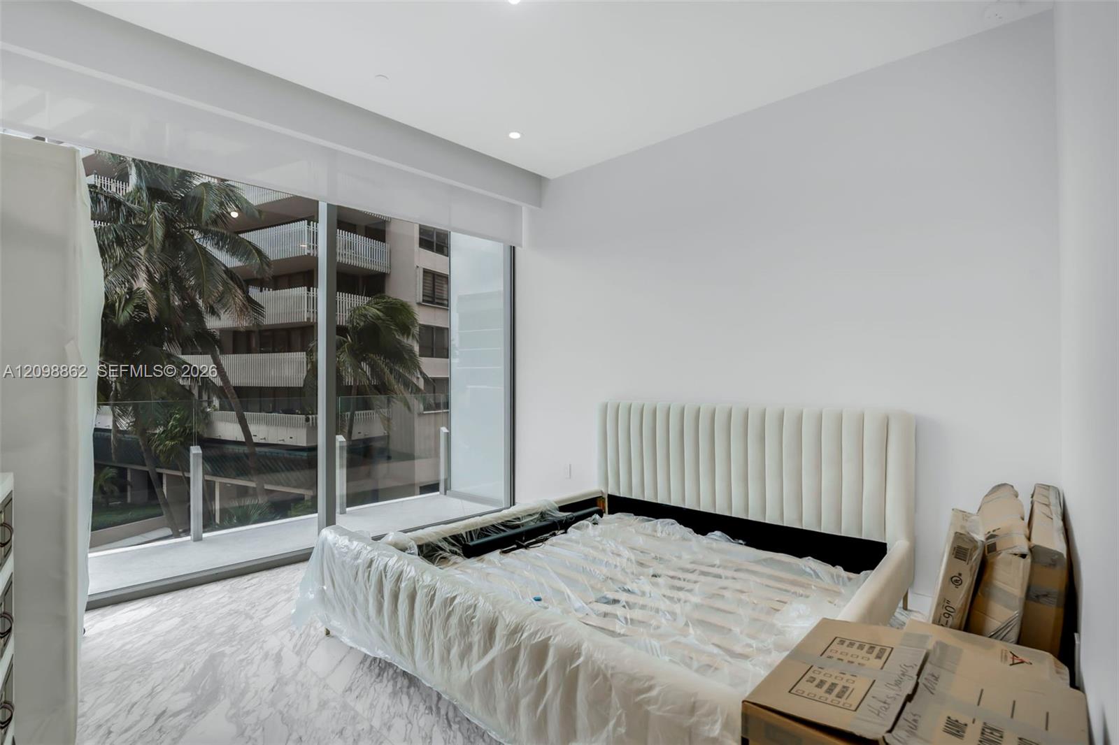 Floor-to-ceiling windows, white stone-finish flooring, recessed ceiling lighting, and a glass-paneled balcony