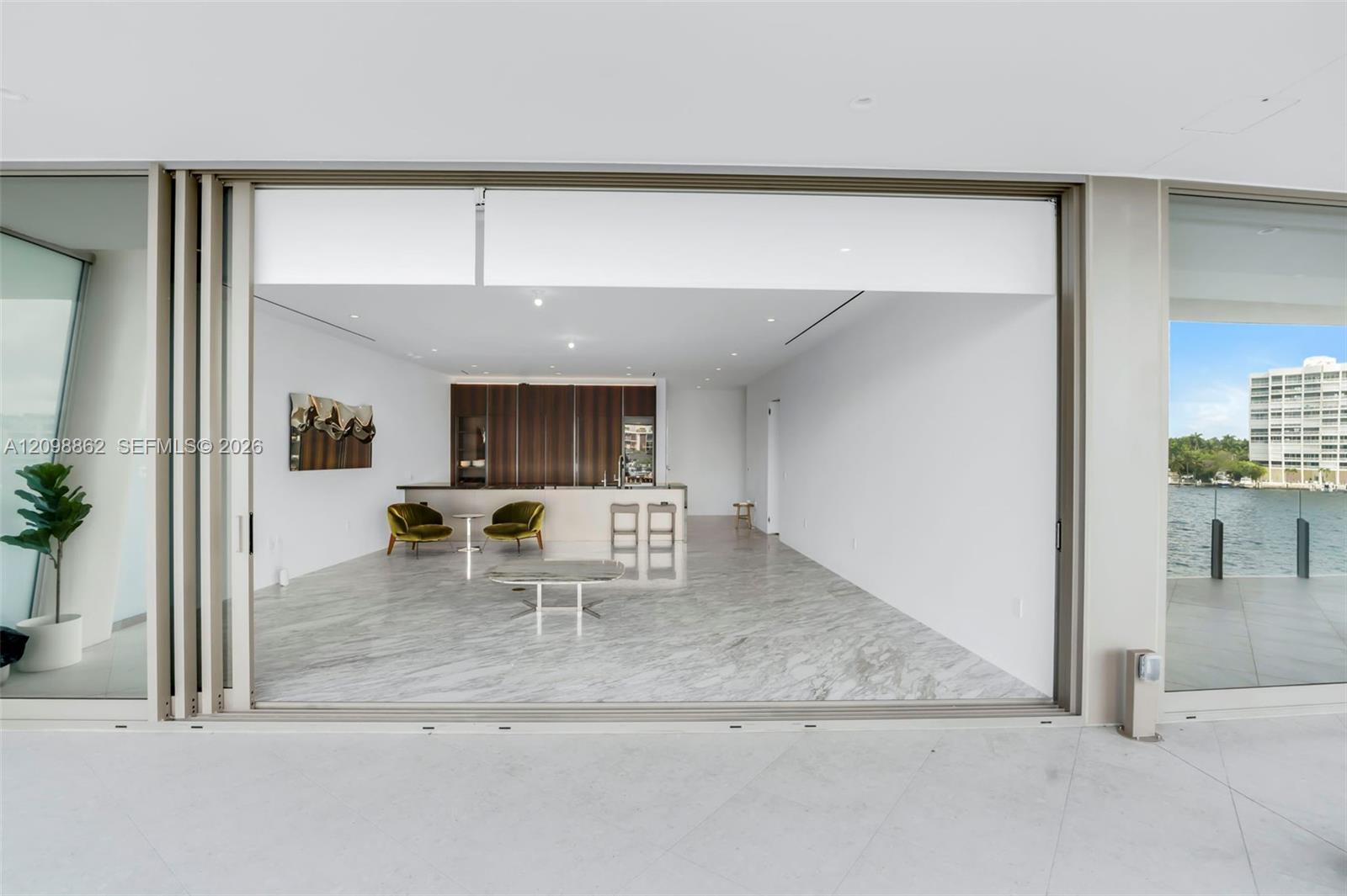 Retractable floor-to-ceiling glass wall, stone-finish flooring, built-in cabinetry, recessed ceiling lighting, and waterfront terrace access Retractable floor-to-ceiling glass wall, stone-finish flooring, built-in cabinetry, recessed ceiling lighting, and waterfront terrace access