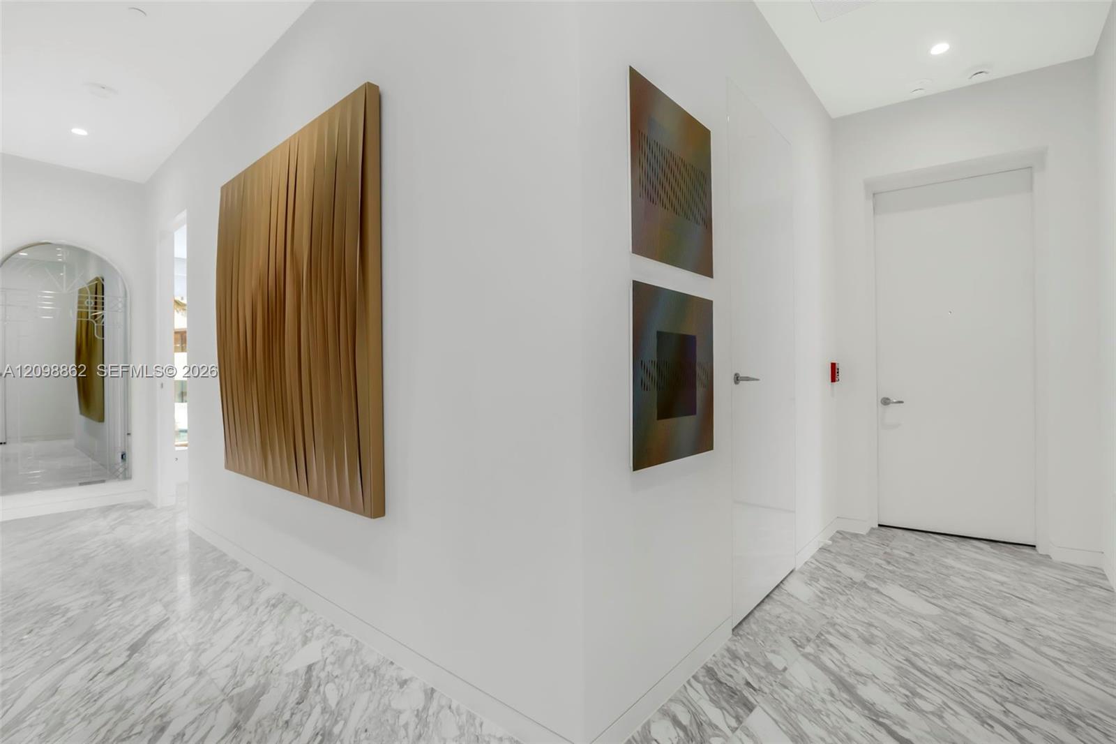 Foyer featuring stone flooring with a neutral veining pattern, recessed ceiling lighting, arched doorway, and solid-core interior doors with satin-finish hardware