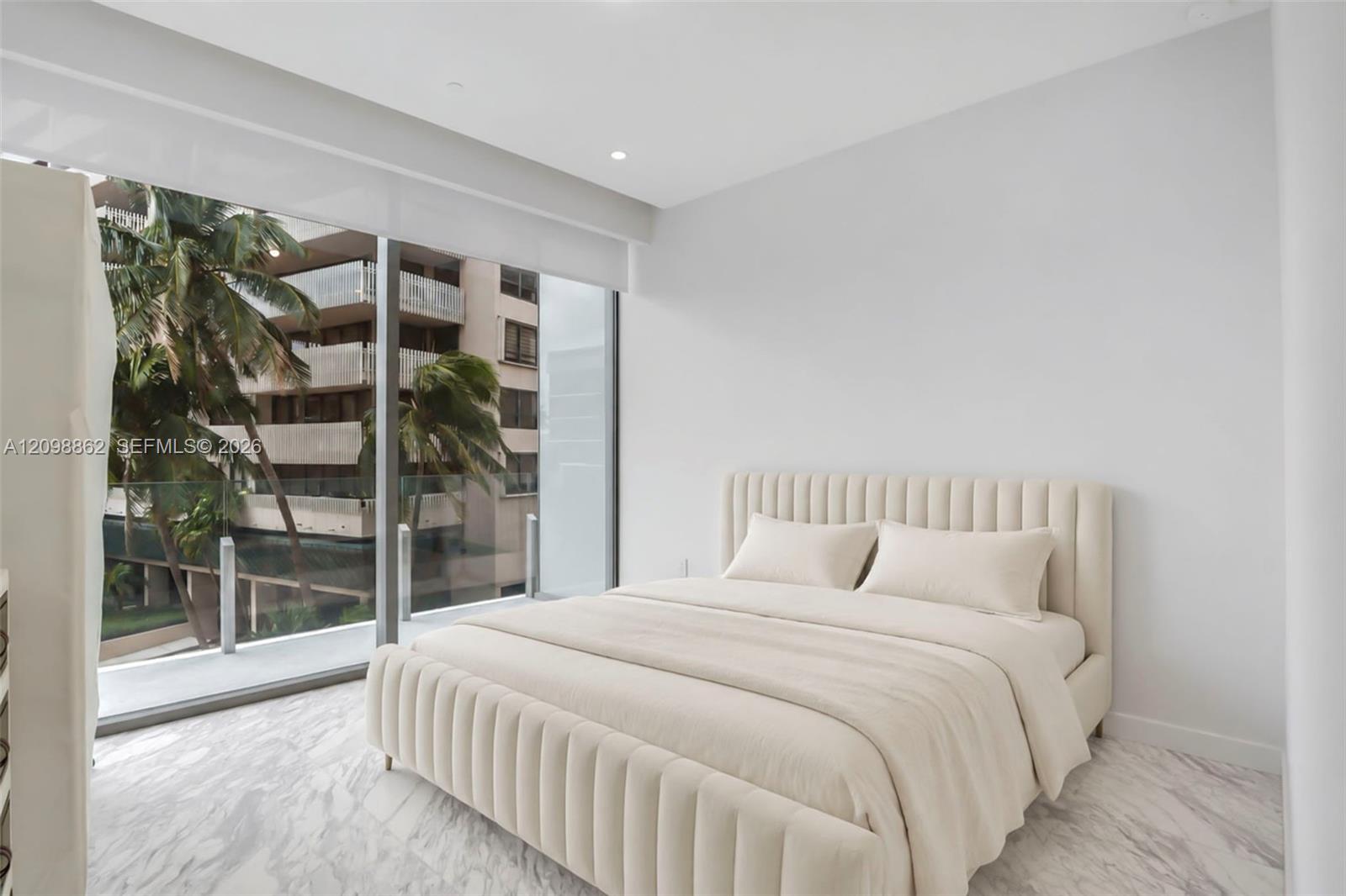 Floor-to-ceiling glass sliding doors, private balcony with metal railing, stone-finish flooring, and recessed ceiling lighting