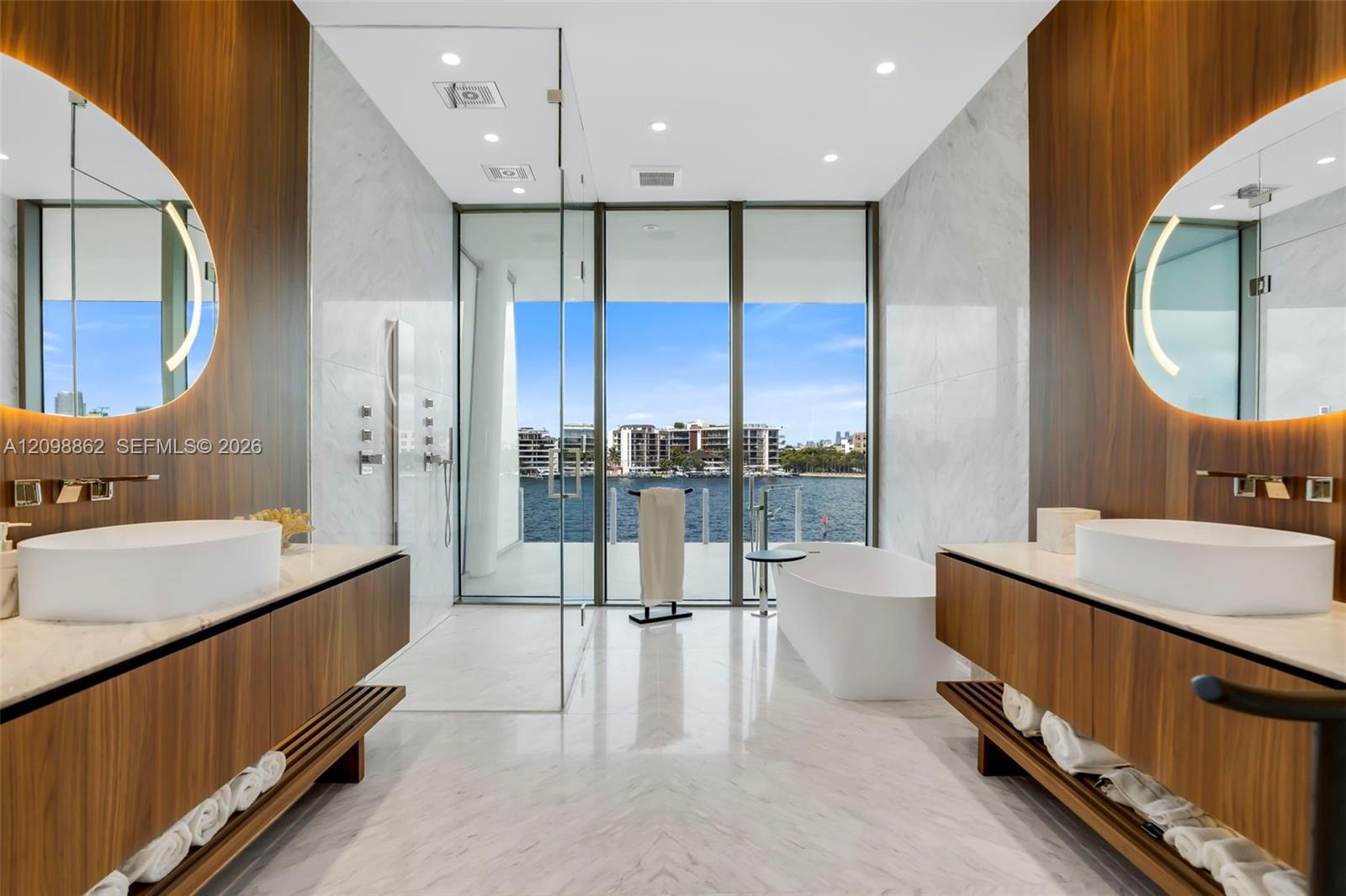 Dual floating vanities featuring wood-finish cabinetry, stone countertops, and integrated LED-backlit mirrors
