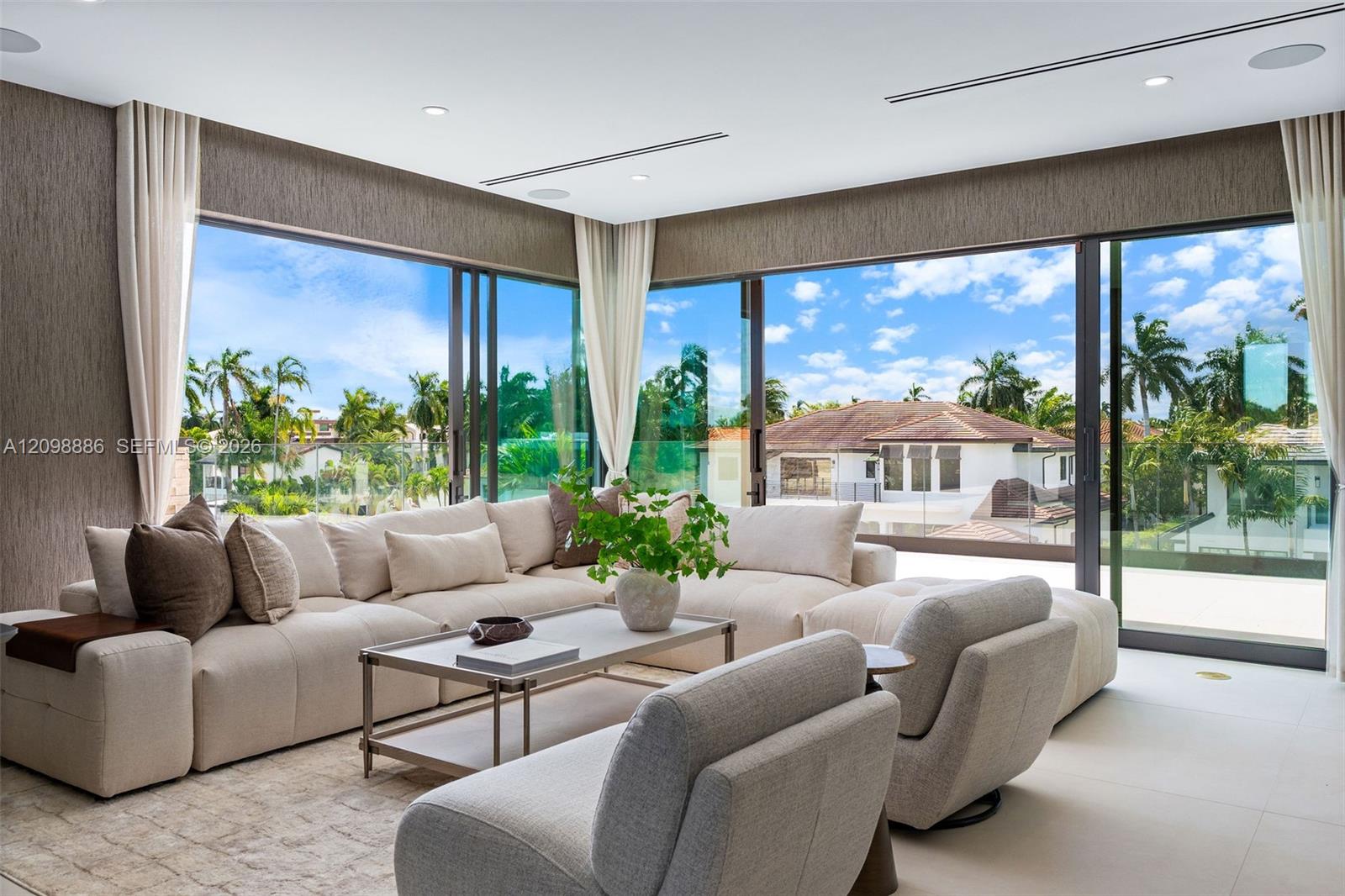 Floor-to-ceiling glass corner walls with multi-panel sliding doors, recessed linear lighting, and large-format tile flooring