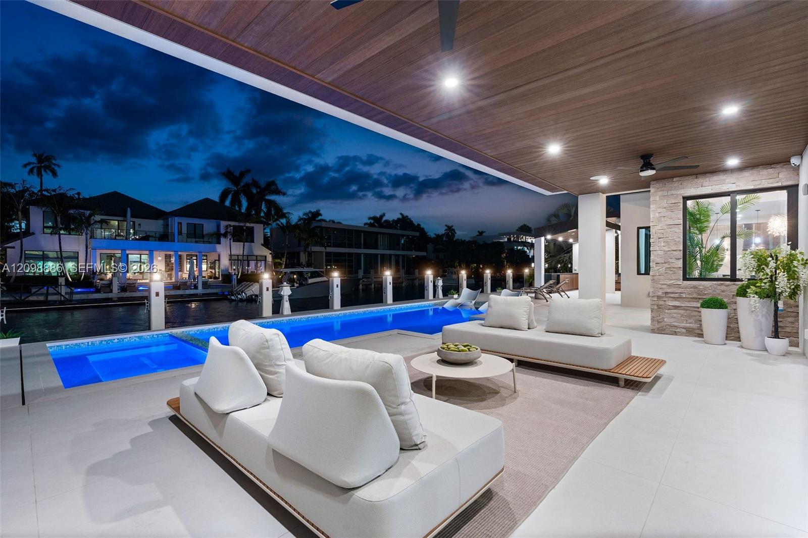 Covered outdoor living area featuring a wood-plank ceiling, recessed lighting, tile flooring, stone-veneer accent wall, and a rectangular swimming pool