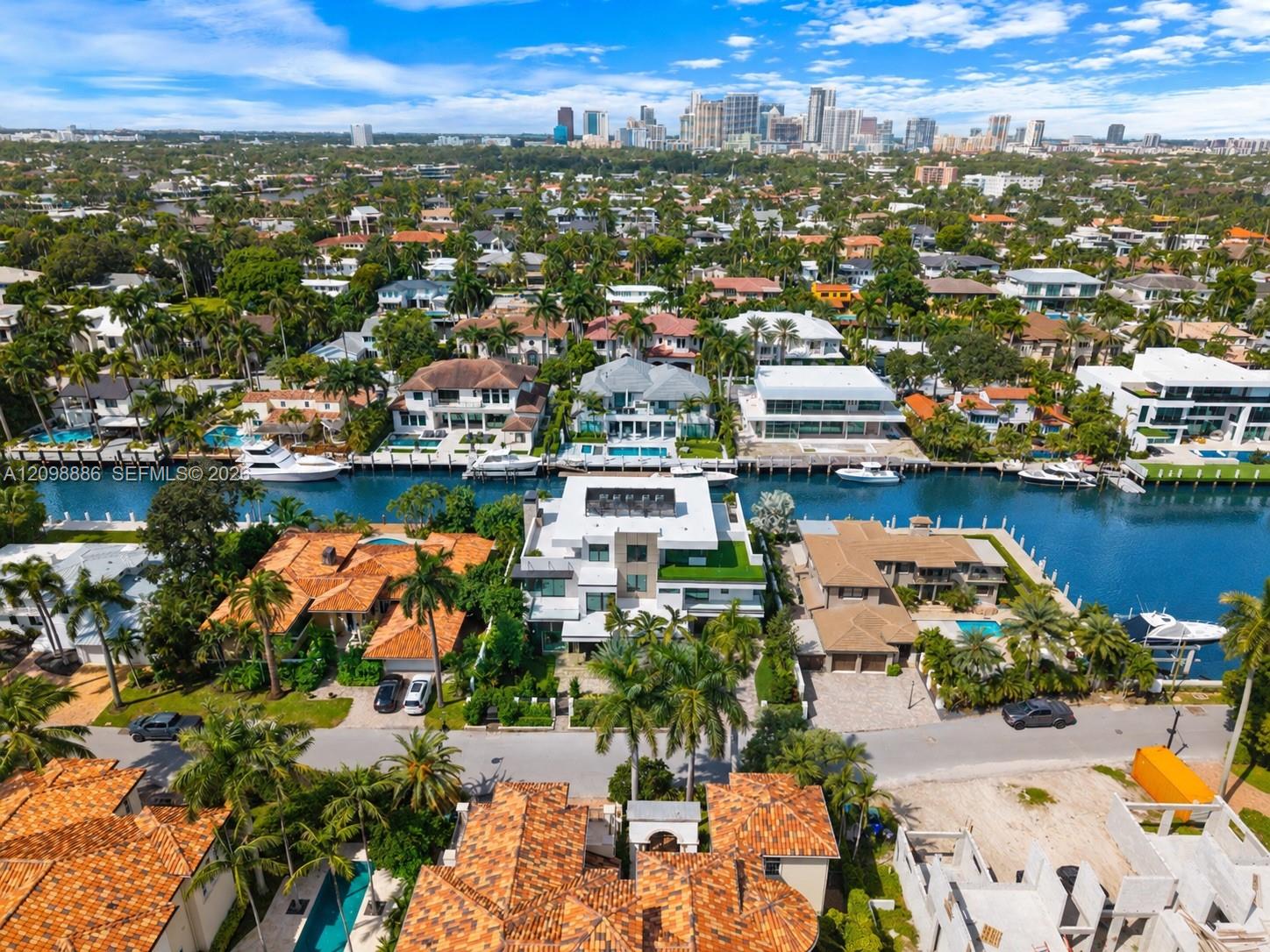 Aerial perspective of waterfront property featuring deep-water canal access, private boat dockage, and a multi-level structure with roof terrace and flat-roof architecture