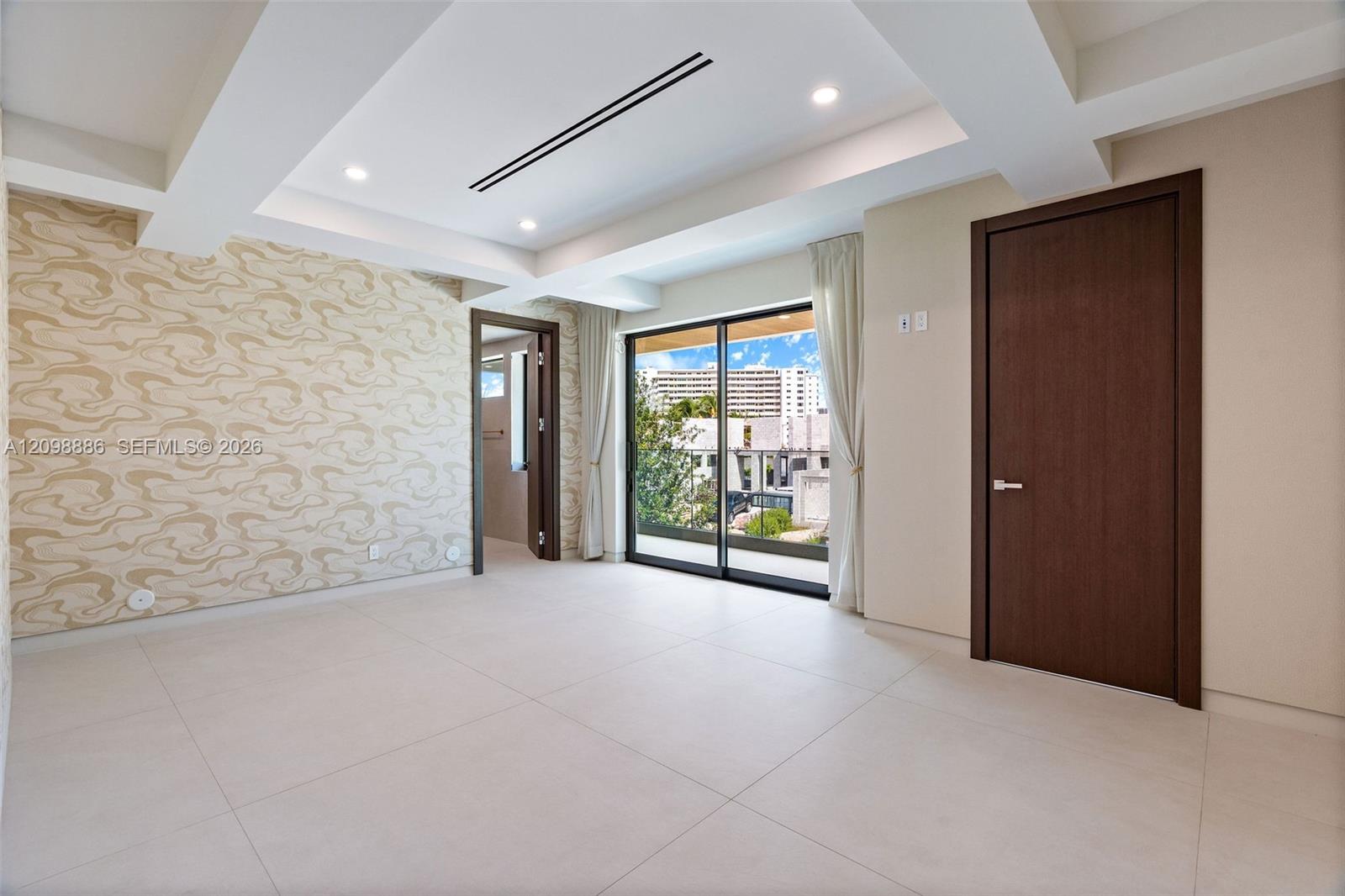 Tray ceiling with recessed lighting, large-format tile flooring, textured wall covering, and sliding glass doors with external access