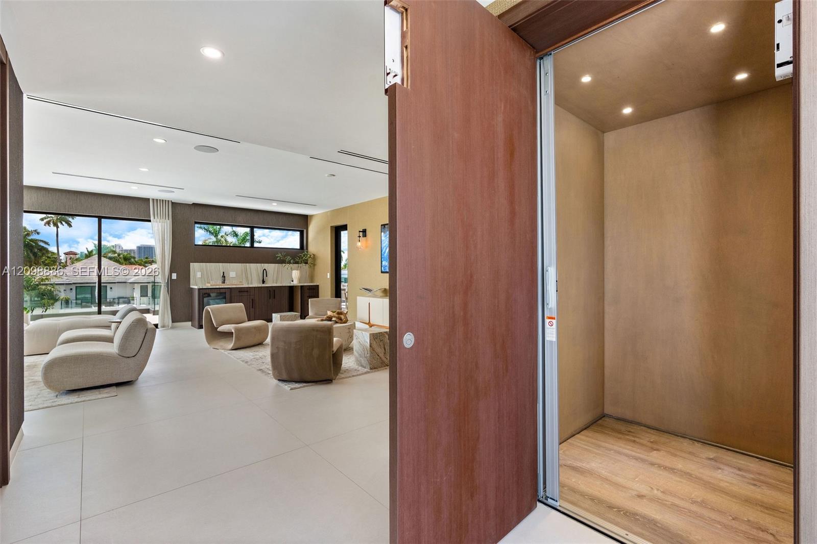Private elevator with wood-panel interior finishes, large-format tile flooring, recessed ceiling lighting, and floor-to-ceiling glass sliding doors