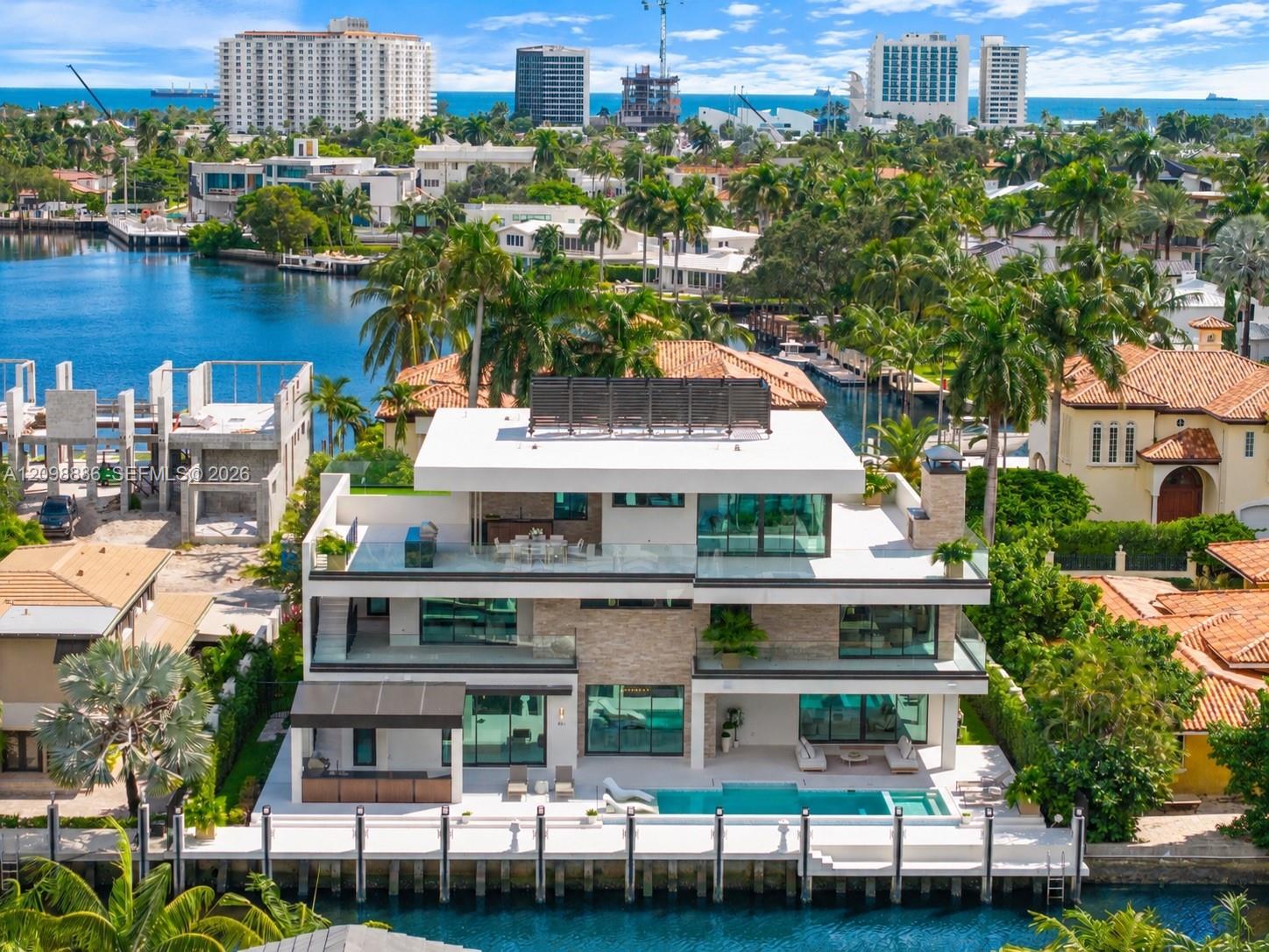 Multi-level waterfront estate featuring a private swimming pool, concrete dock, stacked stone exterior accents, and expansive glass-railed balconies
