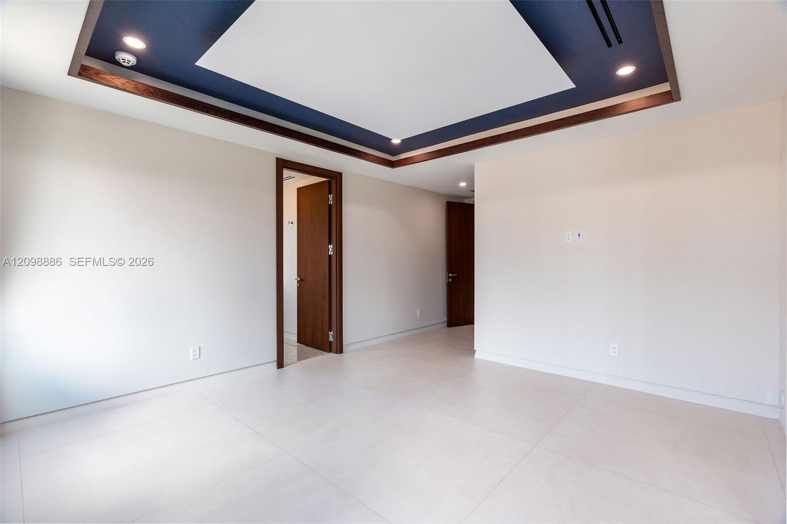 Tray ceiling featuring recessed lighting and dark-toned trim, large-format tile flooring, and solid wood-finish interior doors