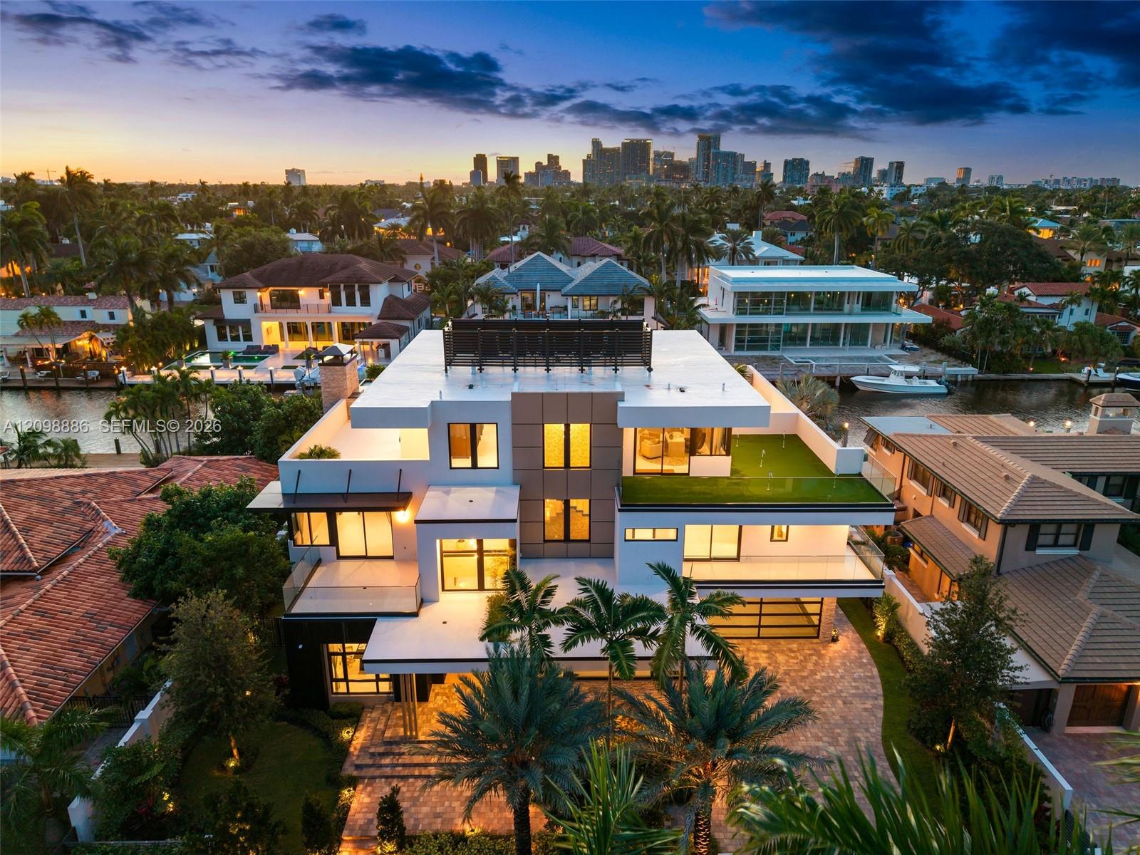 Multi-level contemporary residence featuring a rooftop terrace, tiered balconies with glass railings, composite stone exterior detailing, integrated rooftop solar panels, and paver-stone driveway