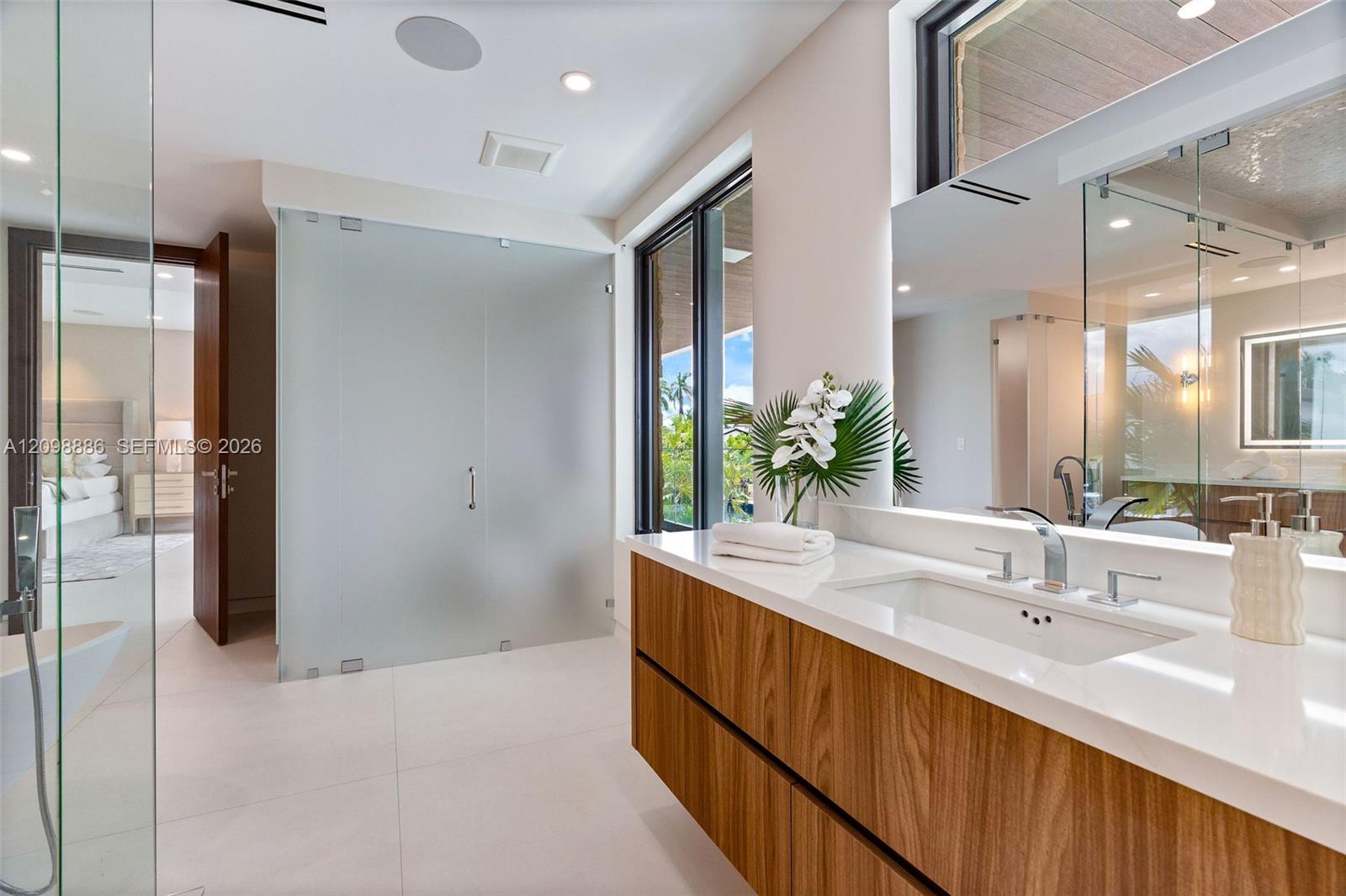 Built-in wood-paneled sauna featuring a glass-door entrance, accompanied by a walk-in shower with a mosaic-tiled accent wall, glass enclosure, transom window, and matte black fixtures