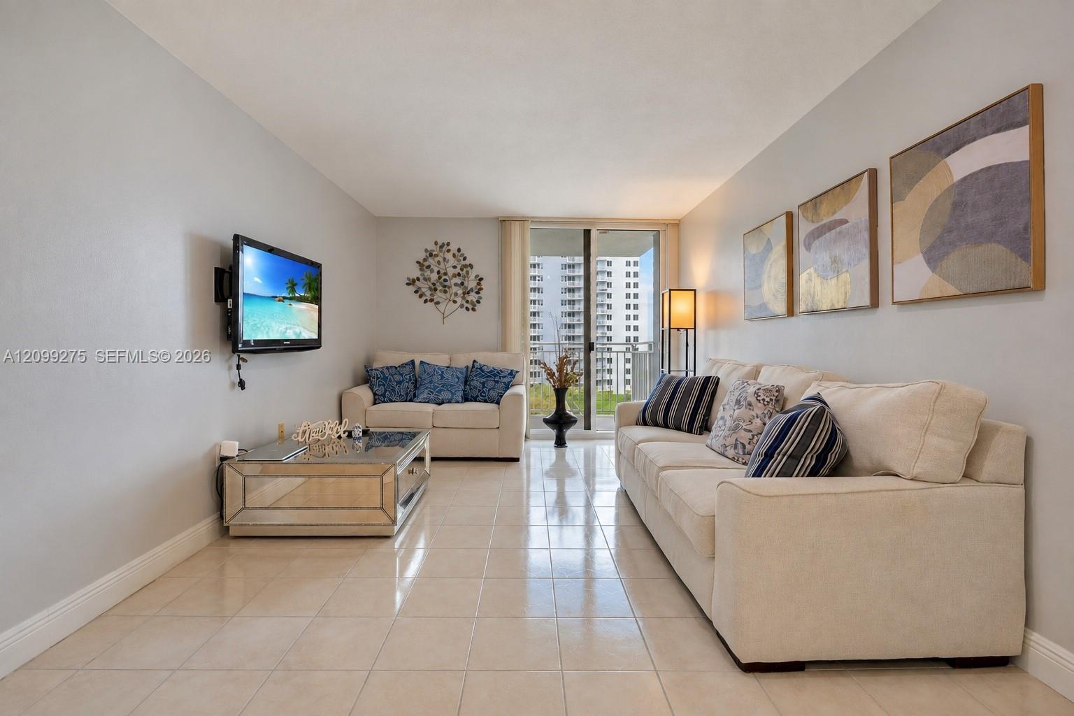 Bright and inviting living room featuring neutral tones, and sliding glass doors opening to a private balcony.