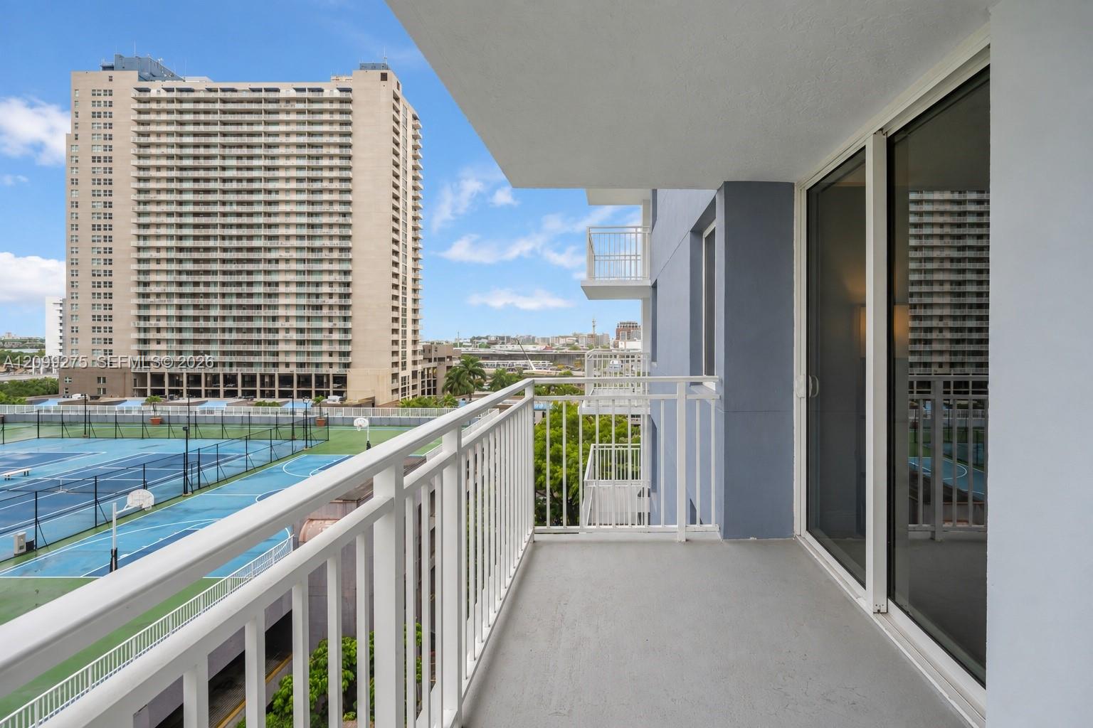 Spacious private balcony featuring white railings and expansive city views, offering an ideal spot to relax and enjoy the open-air setting.