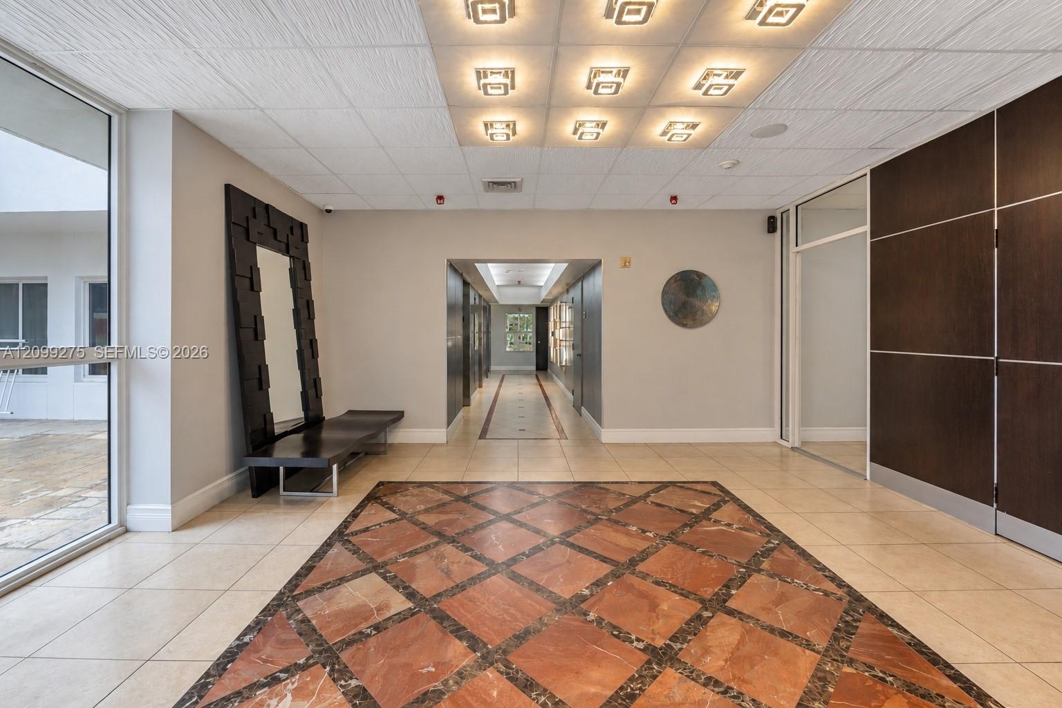 Bright and spacious building entrance foyer featuring elegant tile flooring, comfortable seating, and secure entrance.
