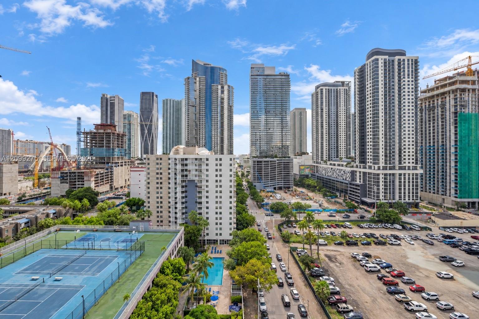 Panoramic city skyline showcasing modern high-rise buildings, with views of the community pool, sports courts, and vibrant urban surroundings.
