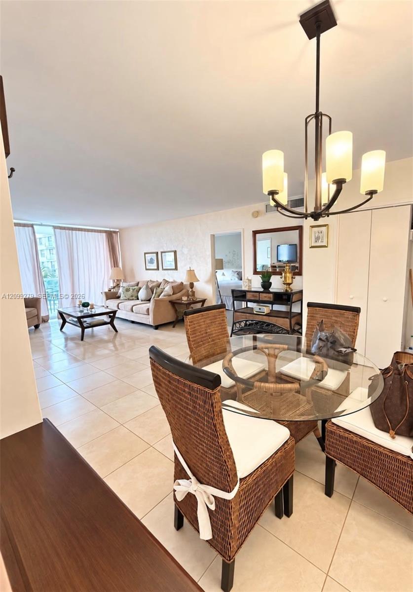 Open-concept living space featuring large-format tile flooring, a multi-light metal chandelier, and floor-to-ceiling glass sliding doors