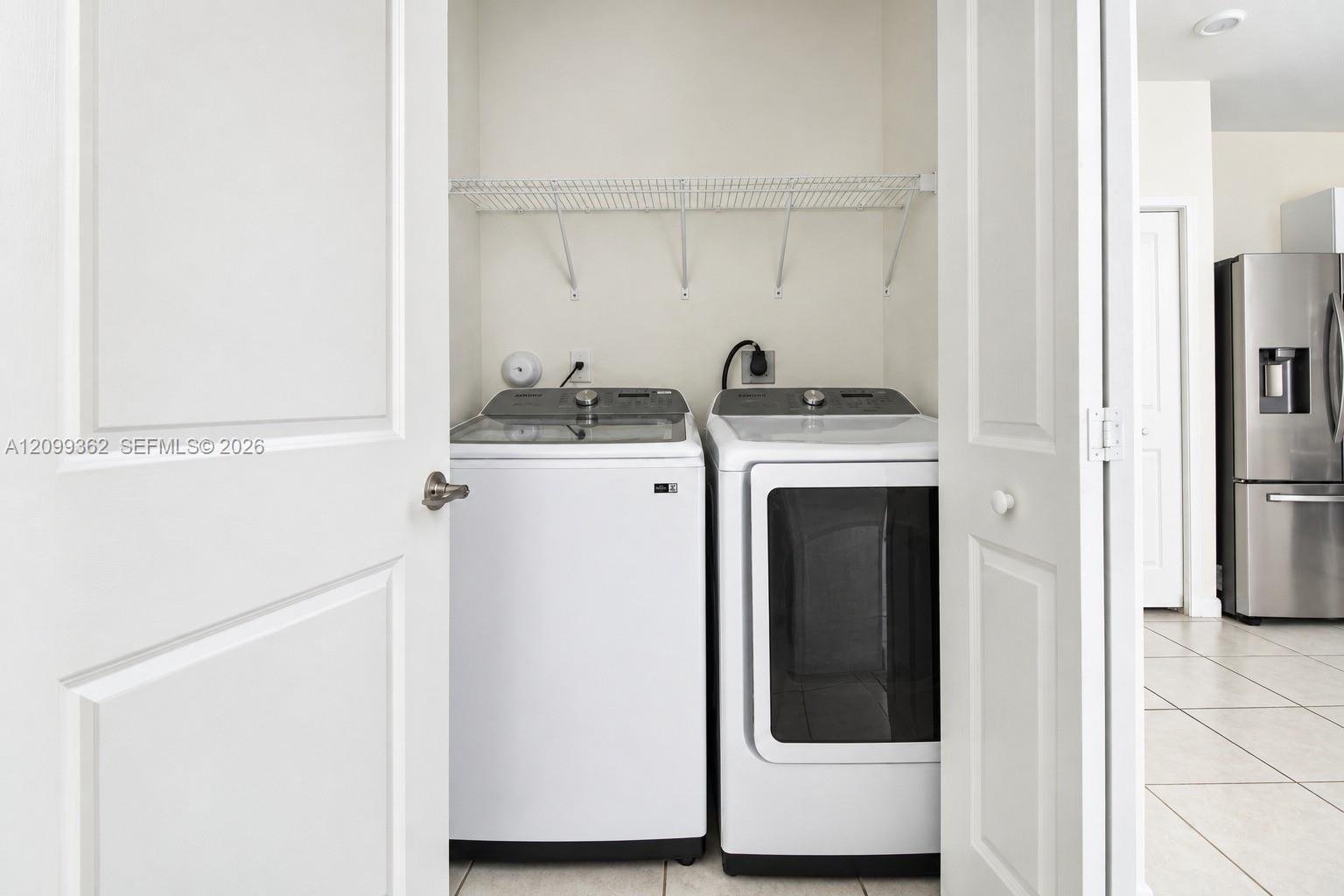 Laundry closet featuring white bifold doors, wire shelving, and tile flooring