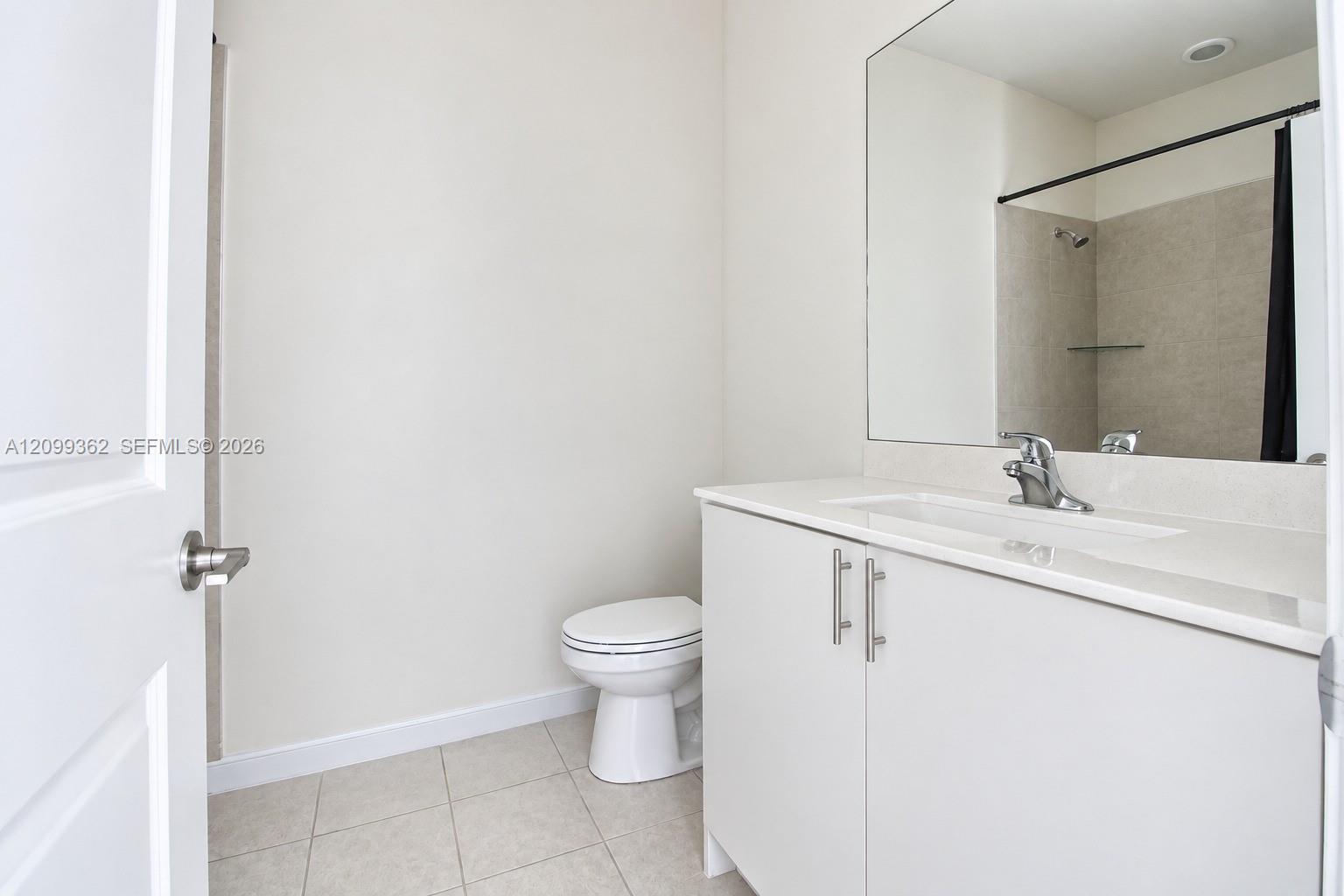 Bathroom featuring a vanity with white cabinetry, light-toned countertop, integrated sink, polished metal faucet, and wall-to-wall mirror