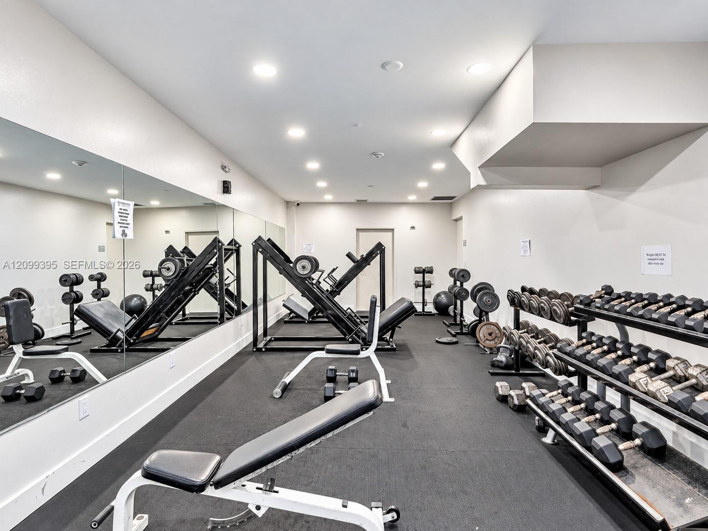 Fitness room featuring recessed lighting, wall-to-wall mirrored surfacing, and resilient rubberized flooring