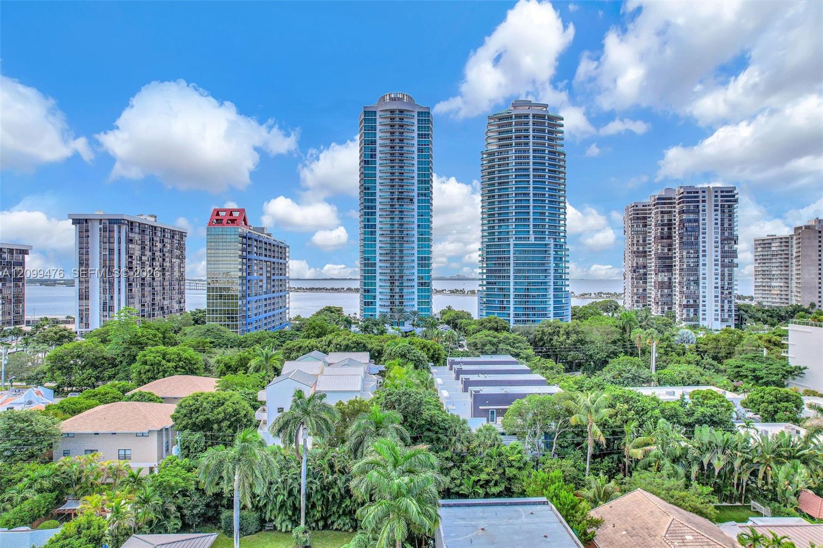 High-rise urban landscape featuring dense canopy vegetation, coastal water, and multi-story structural architecture
