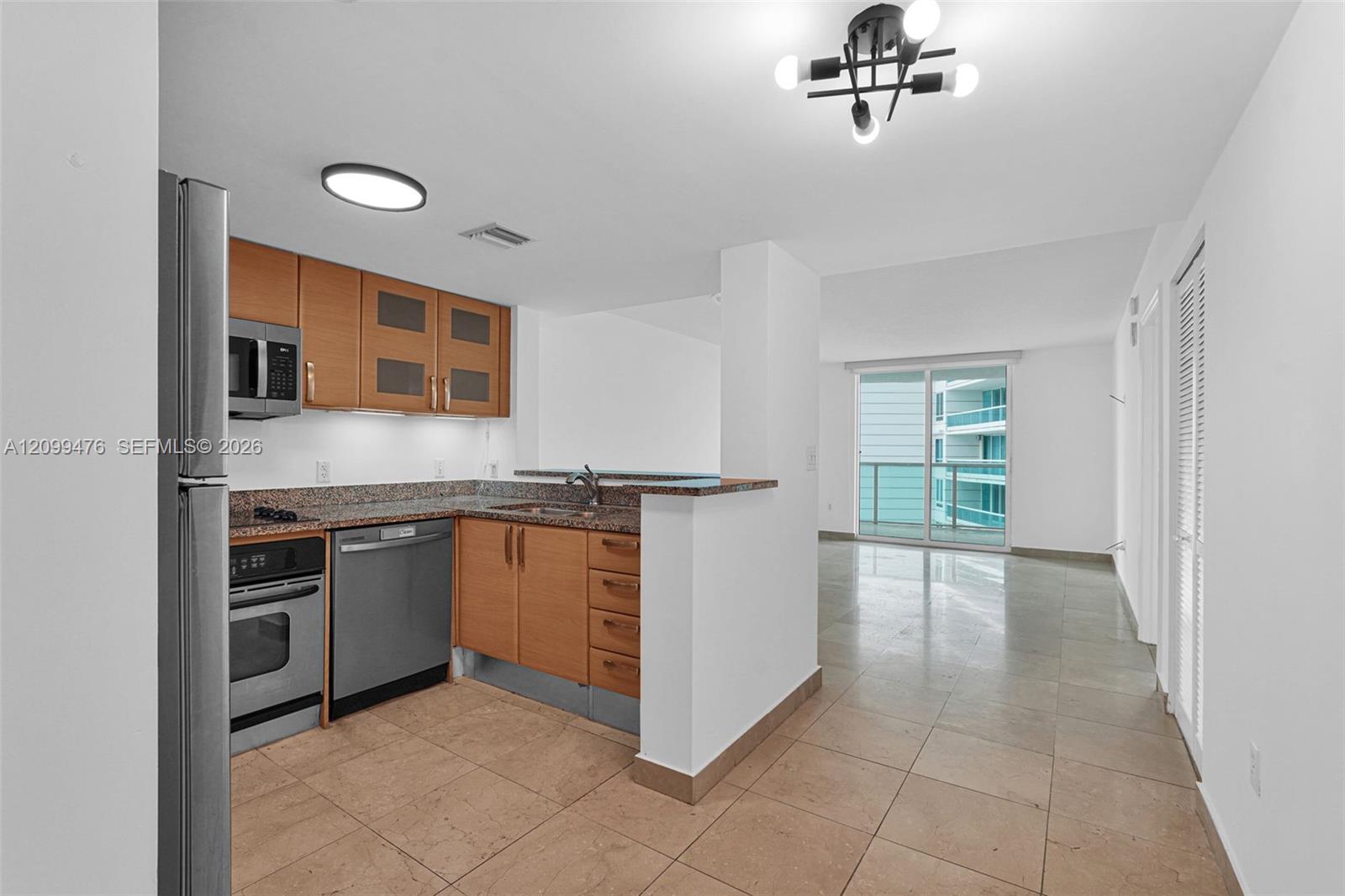 Kitchen featuring wood-finish cabinetry with glass-panel inserts, stone-surface countertops, stainless steel appliances, and tile flooring