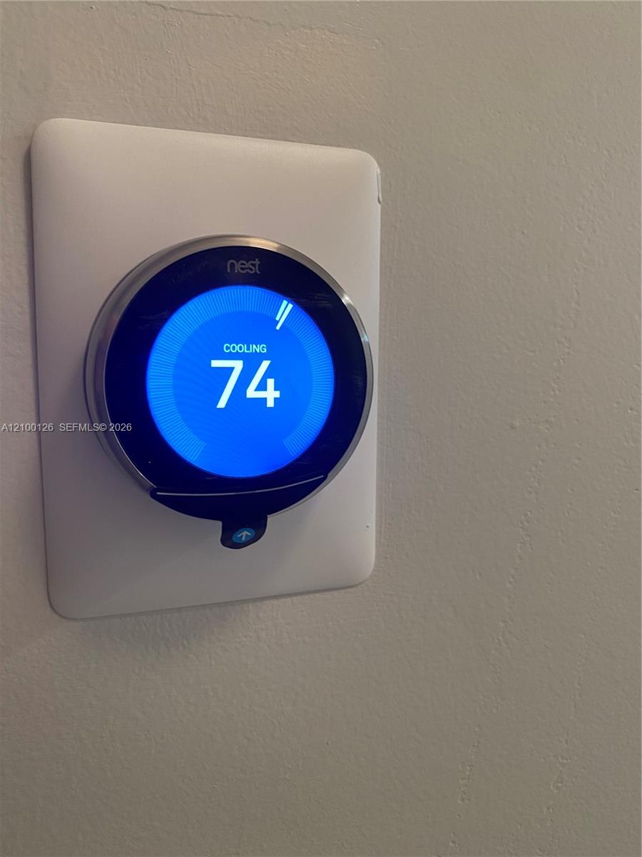 Wall-mounted smart thermostat featuring a digital interface and circular metallic housing