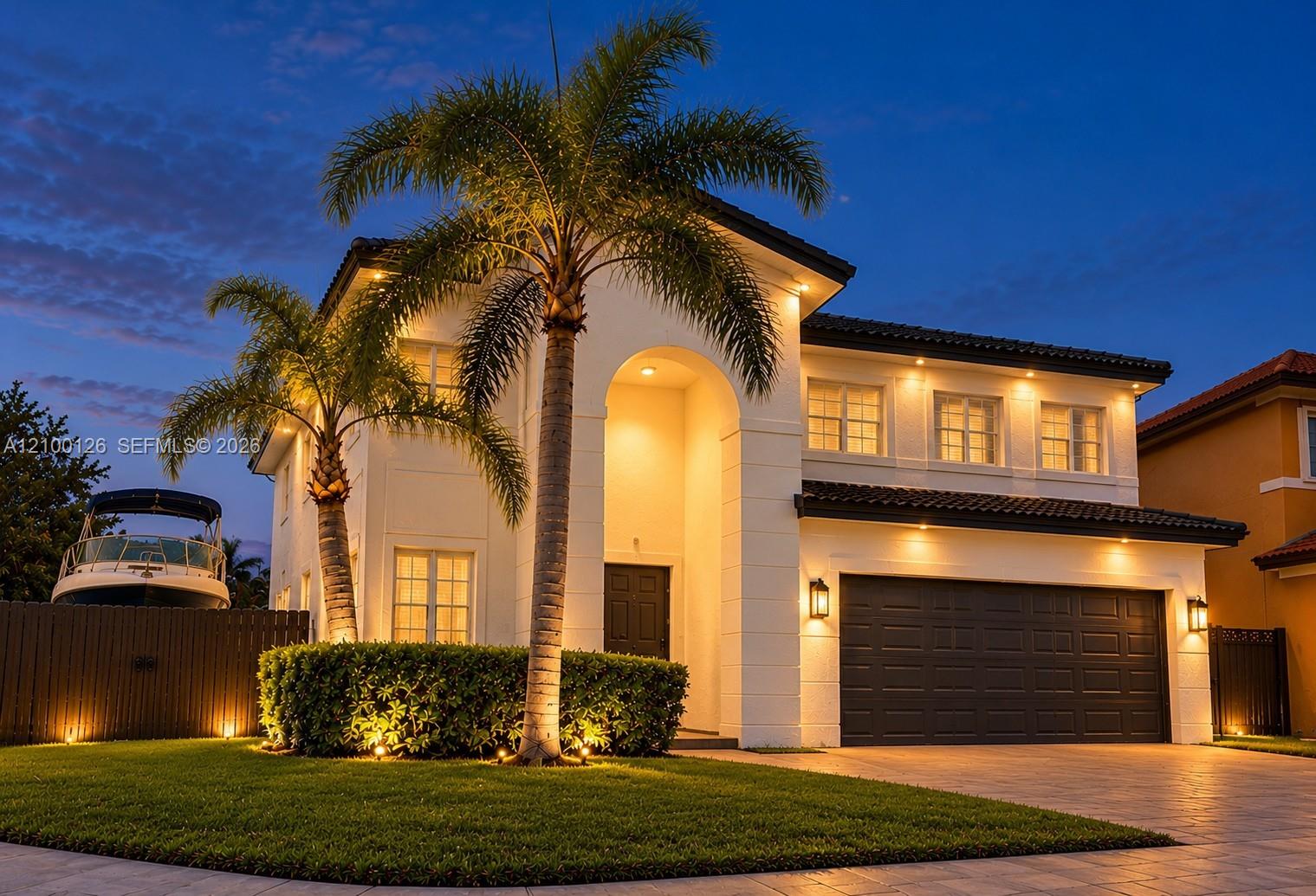Stucco exterior featuring a dual-story arched entryway, tile roof, multi-pane windows, and a paved driveway